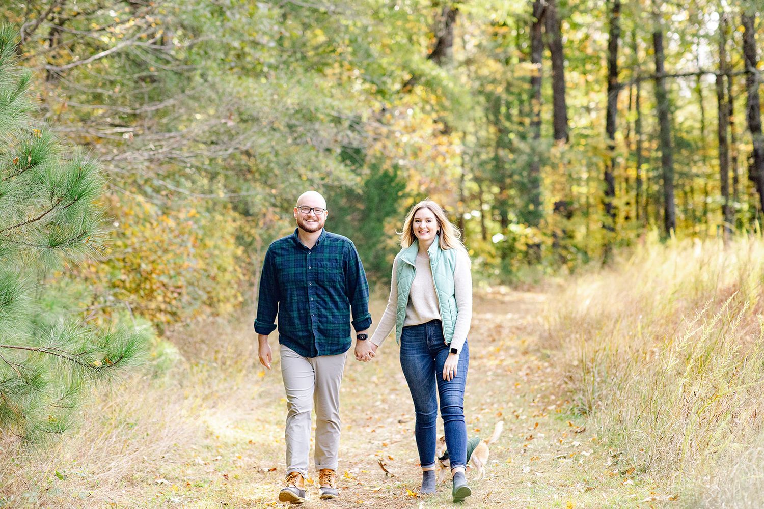 Couple walking hand in hand through a golden autumn meadow.