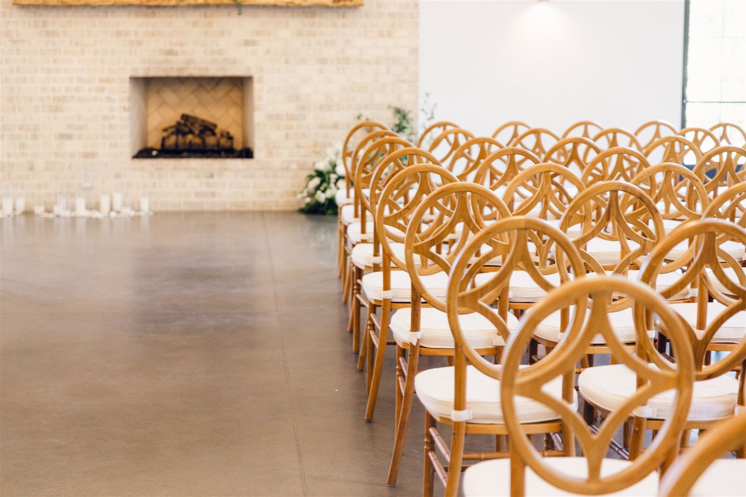 Rows of elegant wooden circular-back chairs arranged in a modern event space with a stone fireplace.