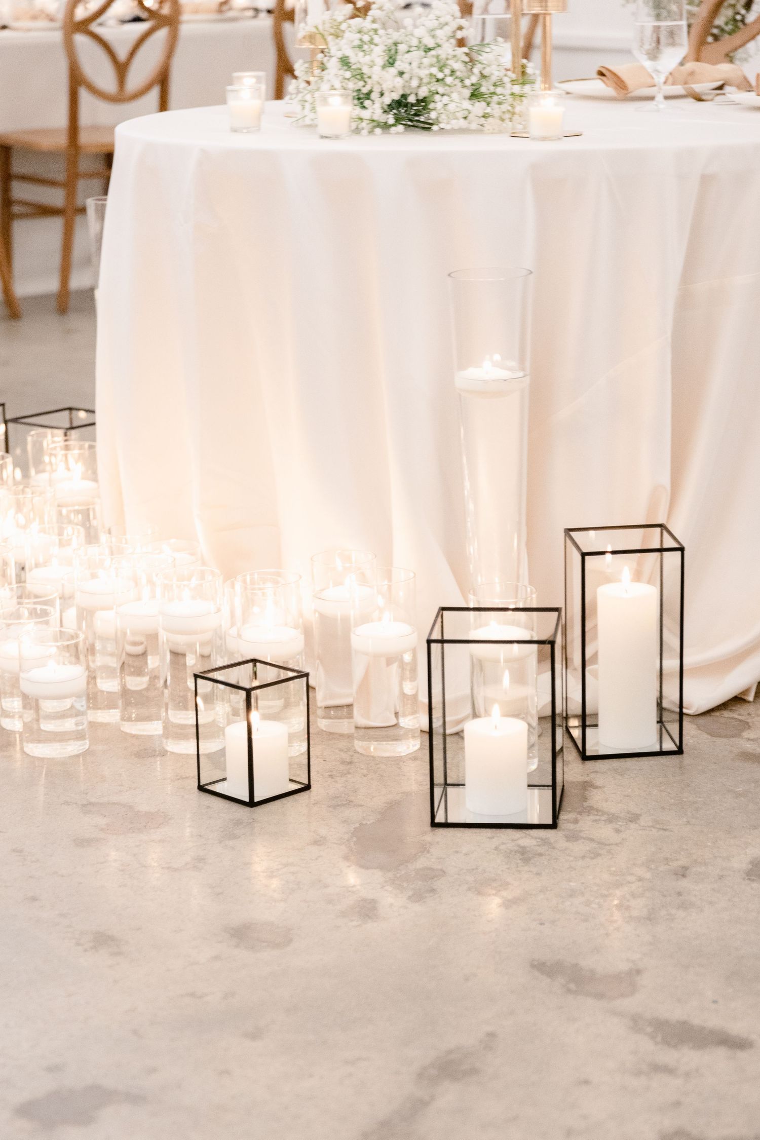 Minimalist black geometric lanterns and glowing candles create an elegant wedding decor display against a light backdrop.