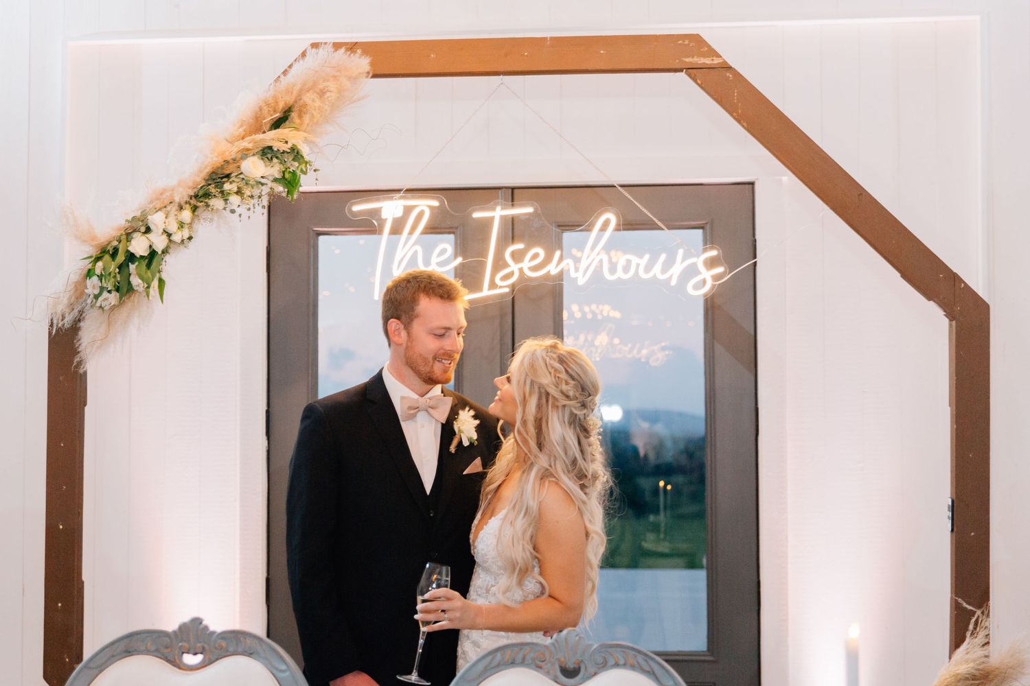 Elegant wedding custom neon sign with brown wooden frame and floral decor displayed at reception.