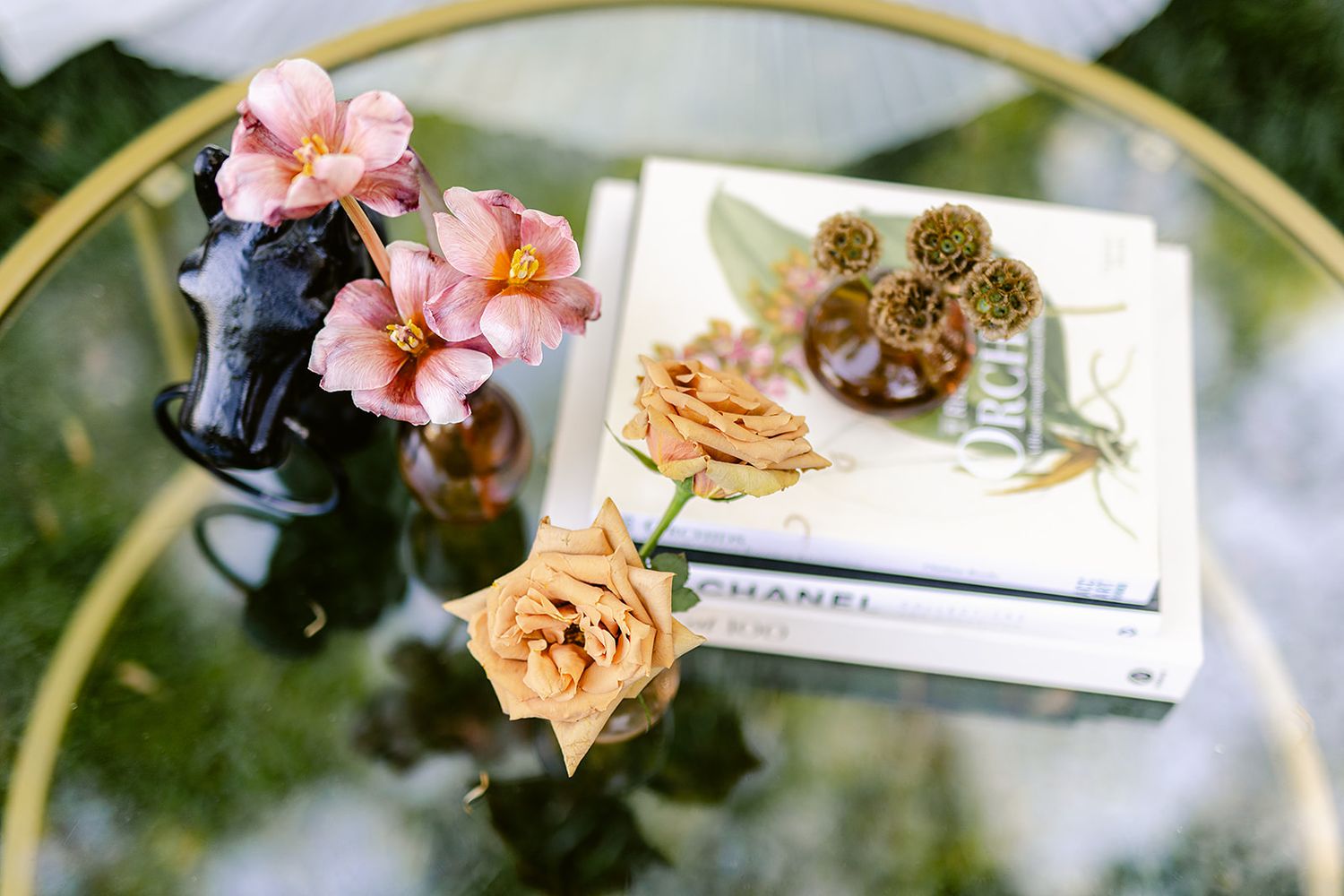 Delicate pink camellia flowers and buds arranged with gold circular frames against a soft green background.