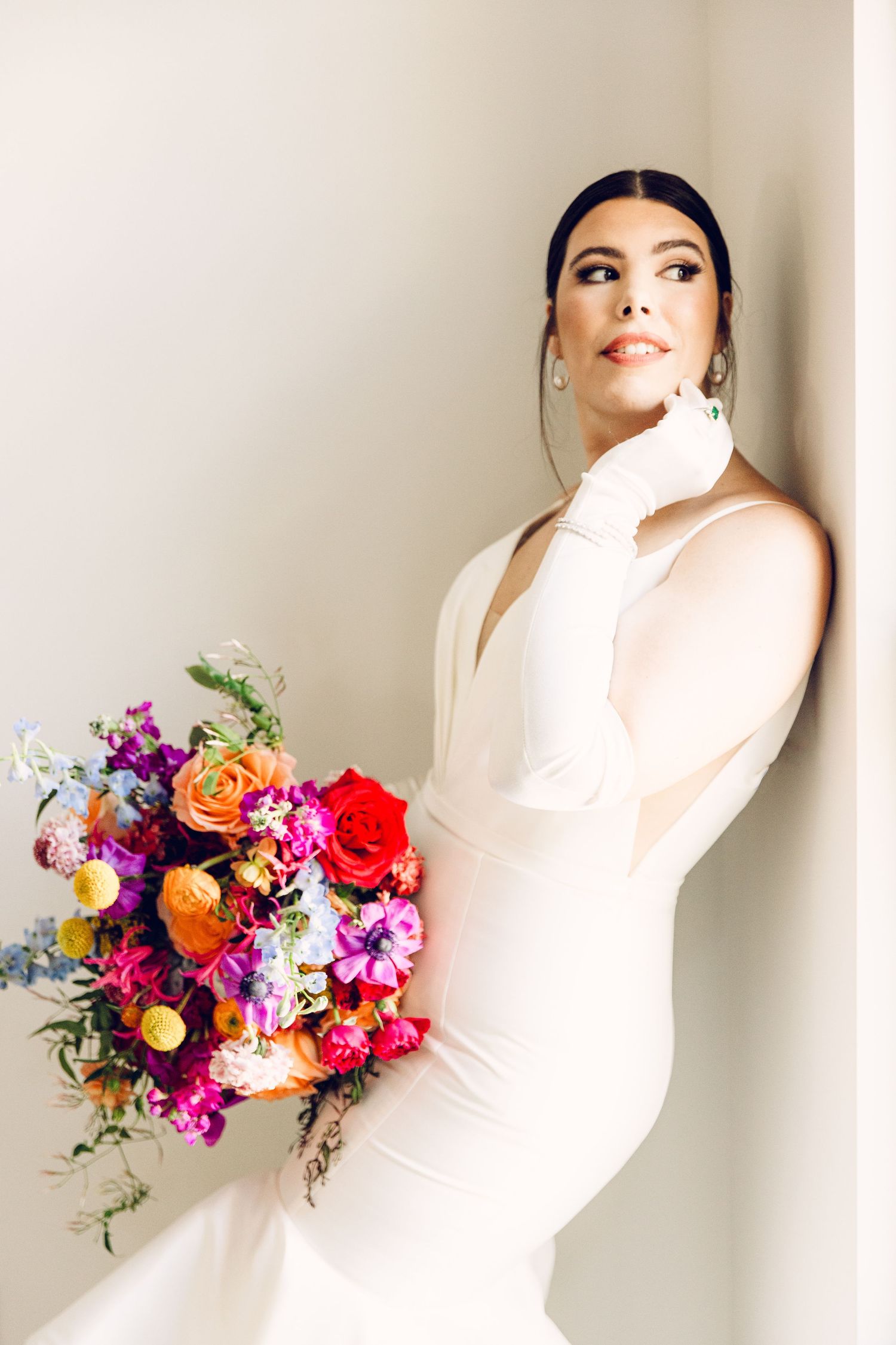 A vibrant bridal bouquet with orange, red, and purple flowers against a white background.