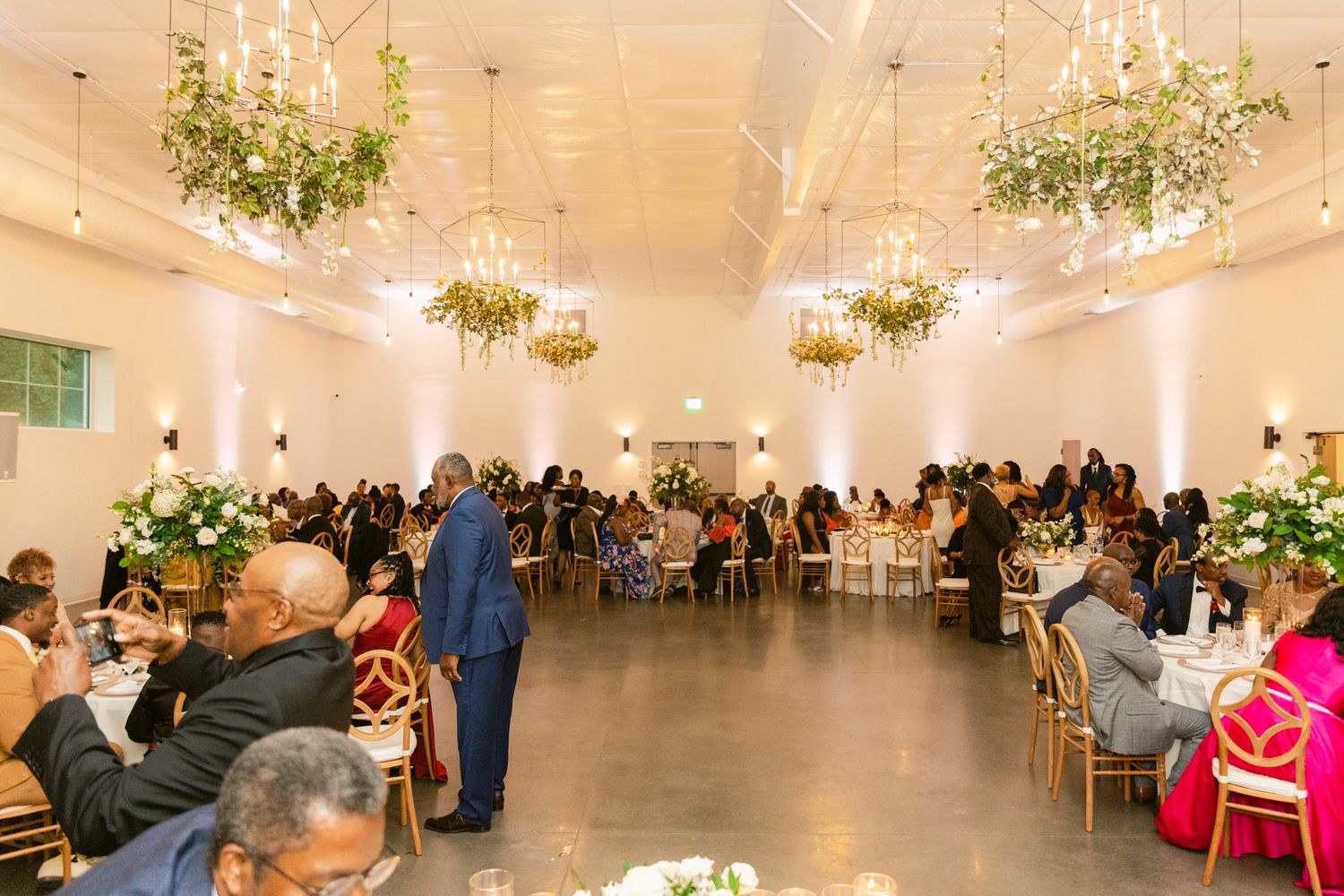 Elegant white wedding reception venue with crystal chandeliers and tables set for a formal celebration.