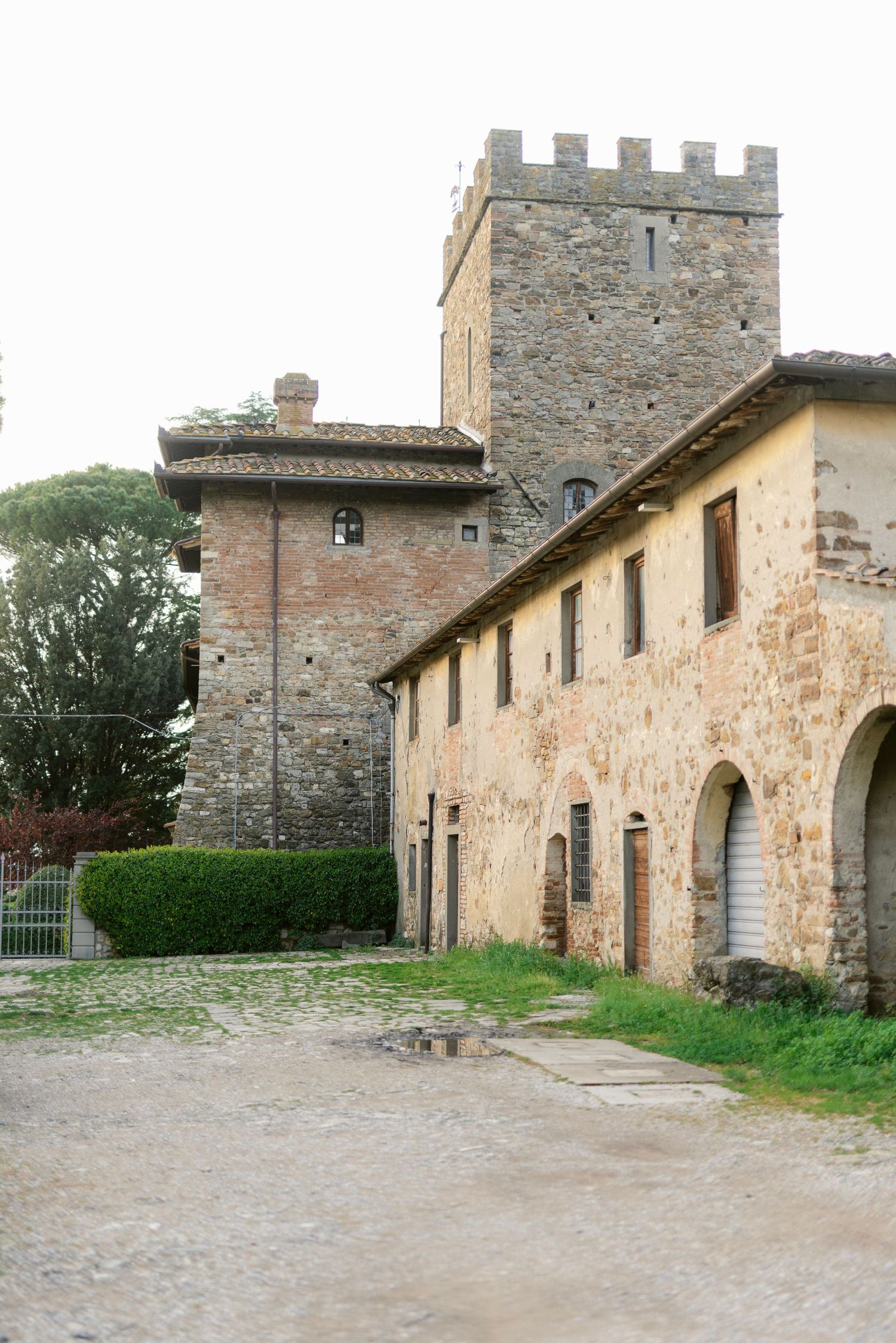 Ancient stone buildings with towers and archways line a rustic courtyard in a medieval Italian village.