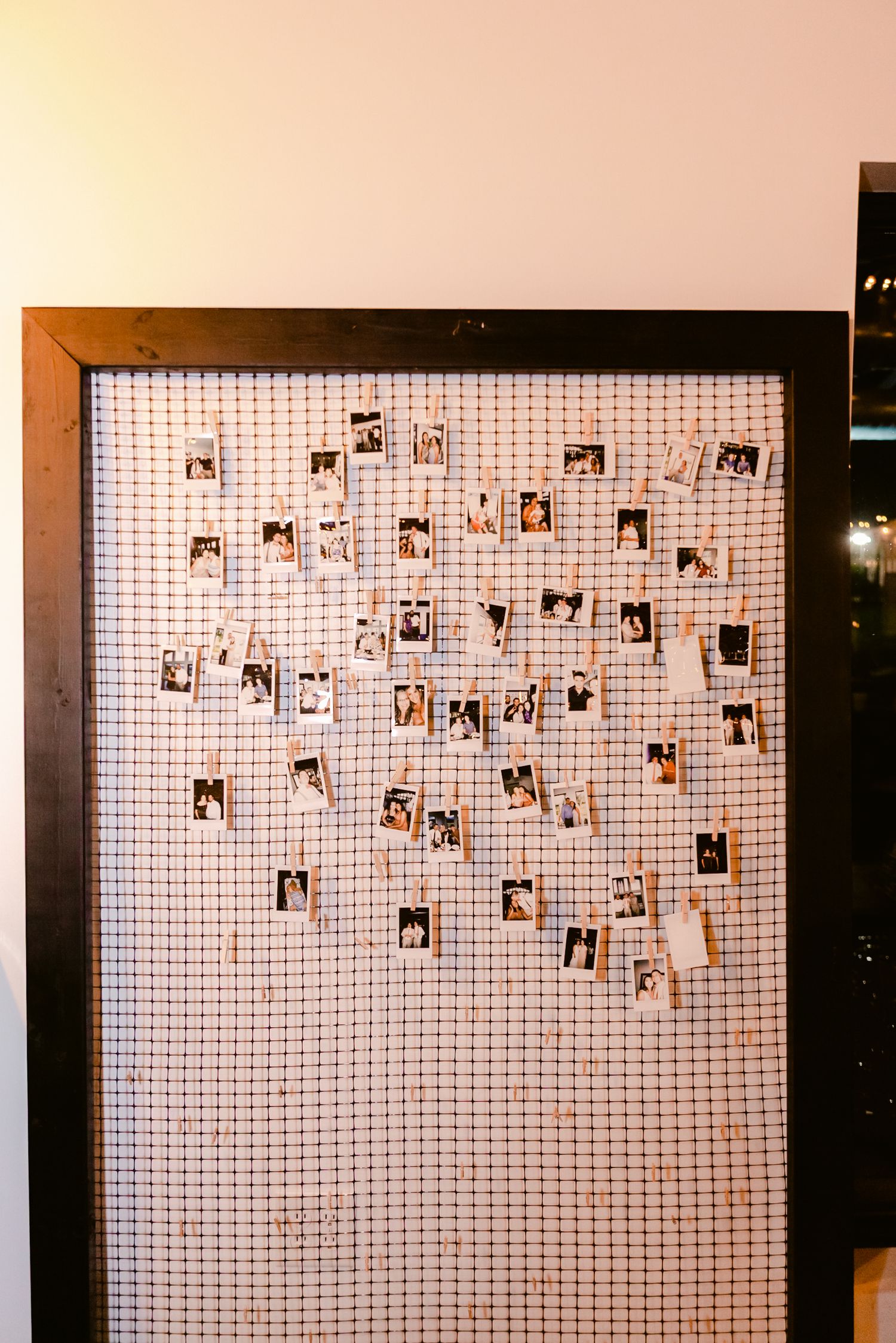 Photo wall display with polaroid-style pictures arranged on a white grid background.
