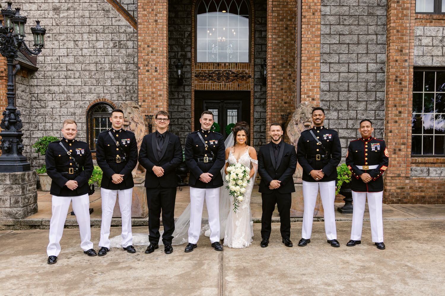 Wedding party members sitting along a brick wall showing their shoes and formal attire in a creative group photo.