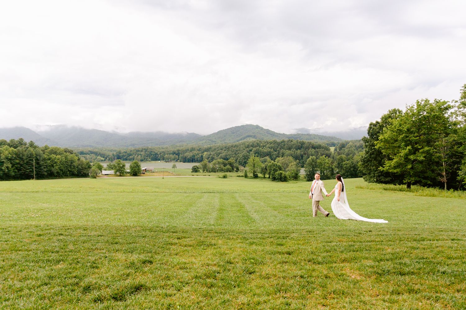 Panoramic view of rolling green hills and mountains under cloudy skies.