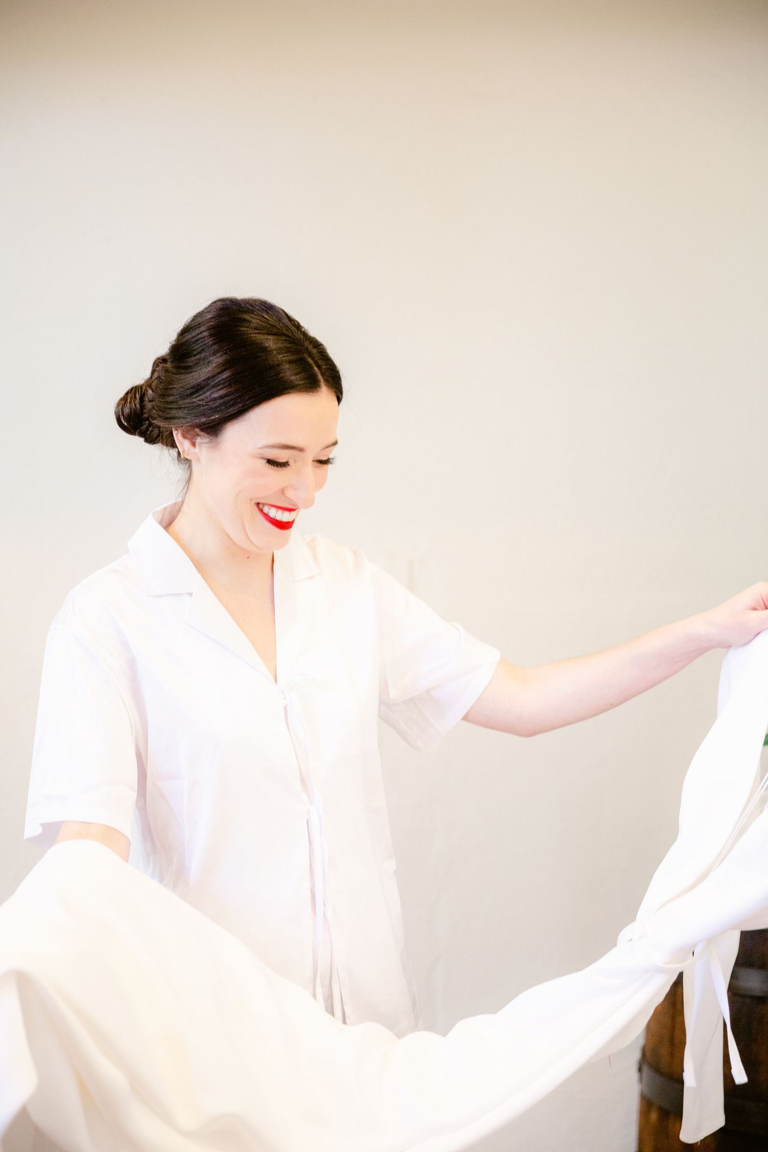 A person in a flowing white dress moves gracefully in a dance-like motion against a neutral background.