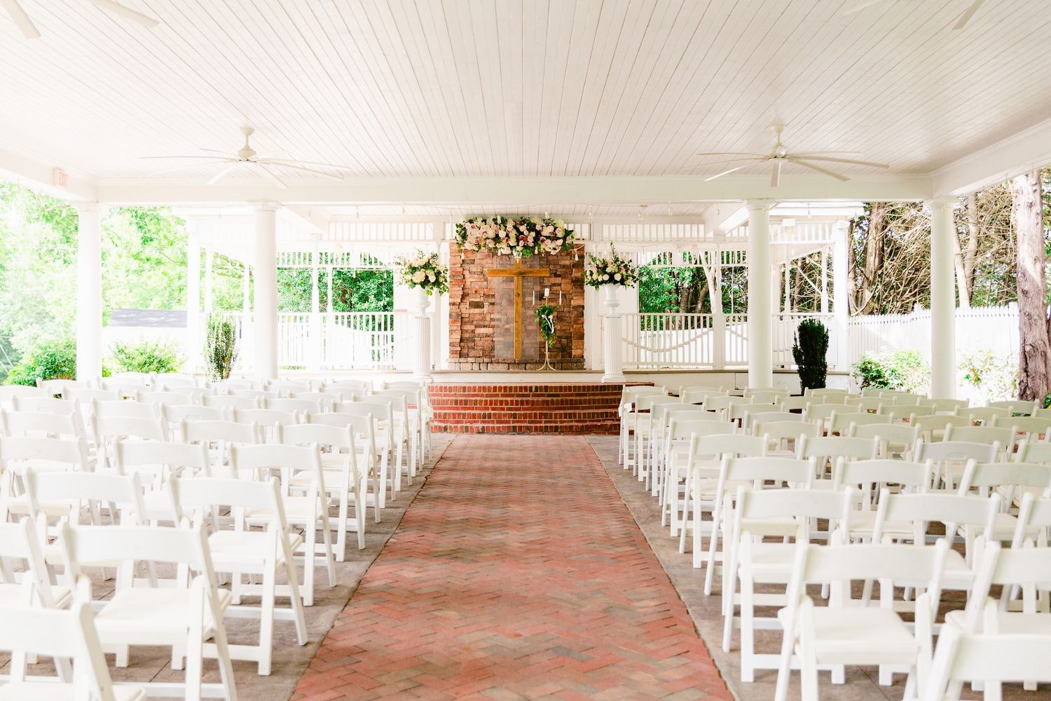 White chairs lined up in rows under an elegant white tent for an outdoor wedding ceremony.
