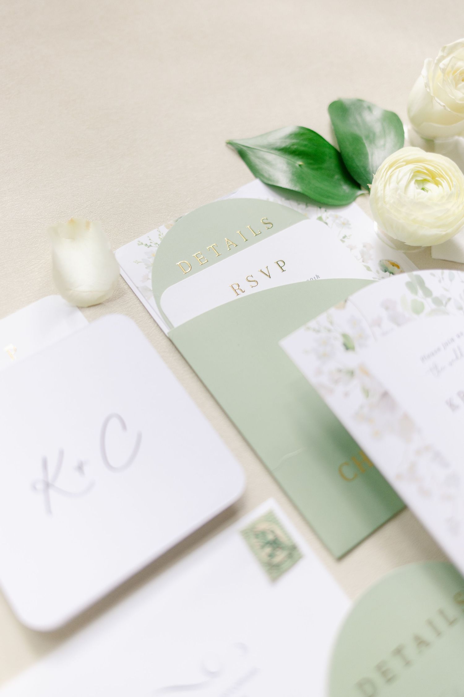 Elegant wedding invitation suite in soft sage green and white with delicate floral details.