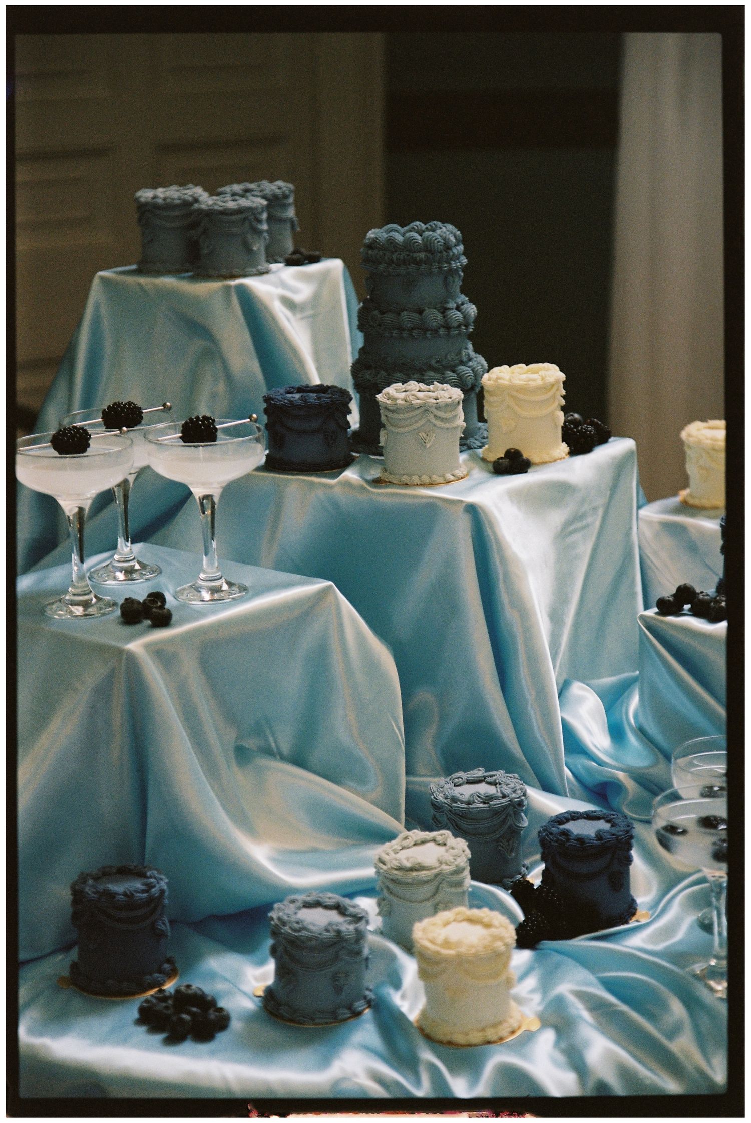 Blue themed wedding set up. Blue silk table cloth. Minature wedding cakes. 35mm film