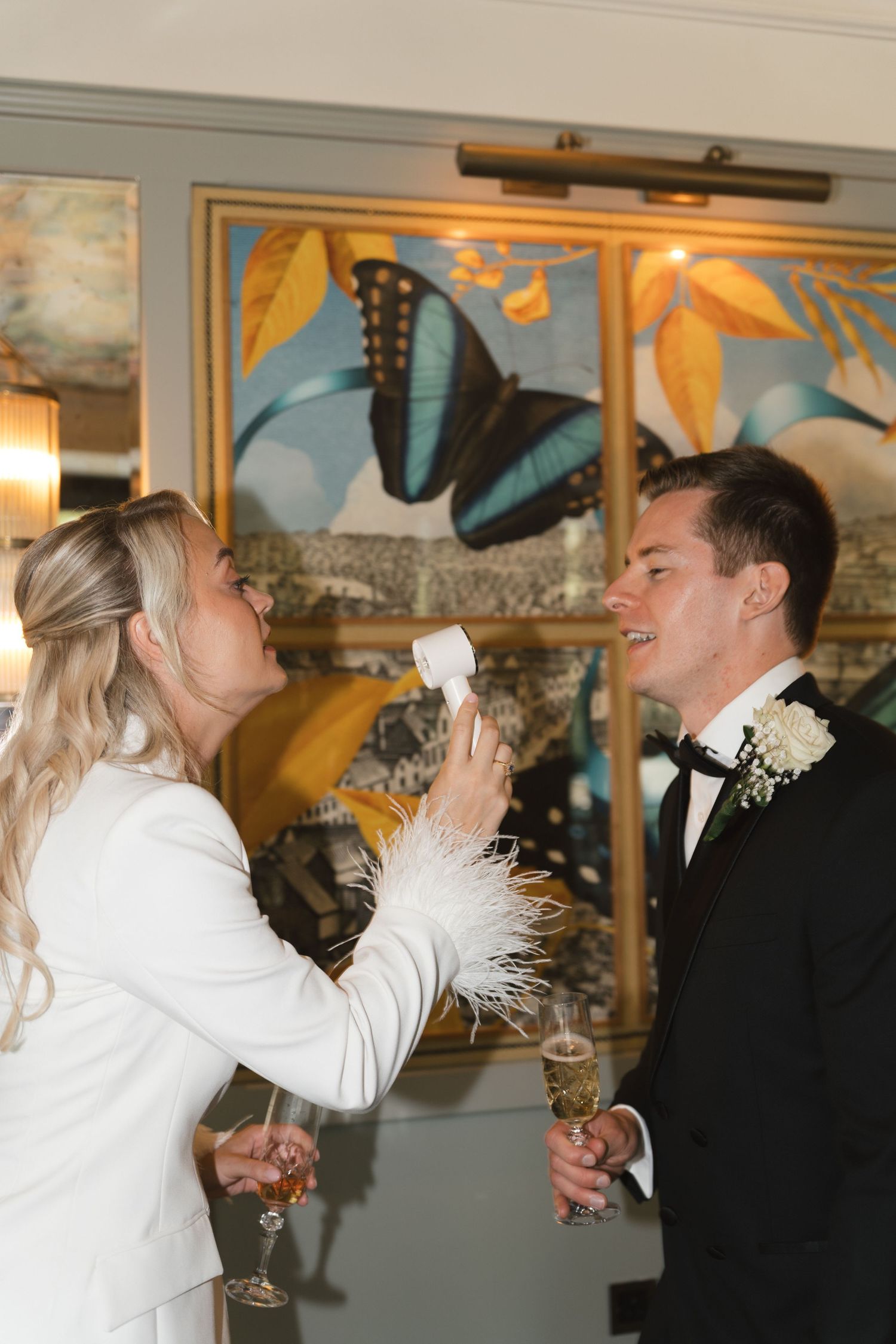 Bride and groom on a hot summers day cooling off with a fan at the Ivy Guildford