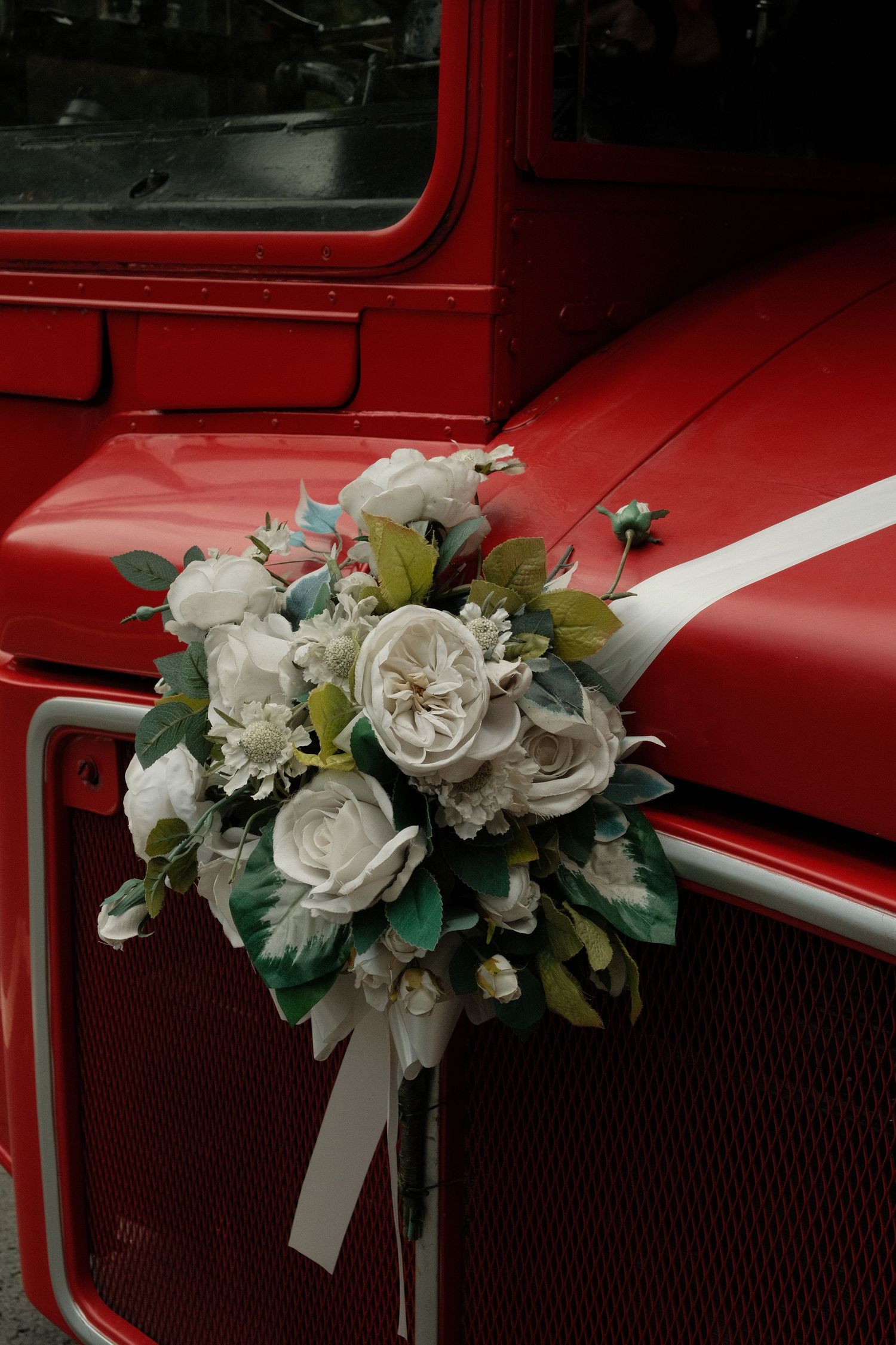 Flowers on the front of a red vintage bus