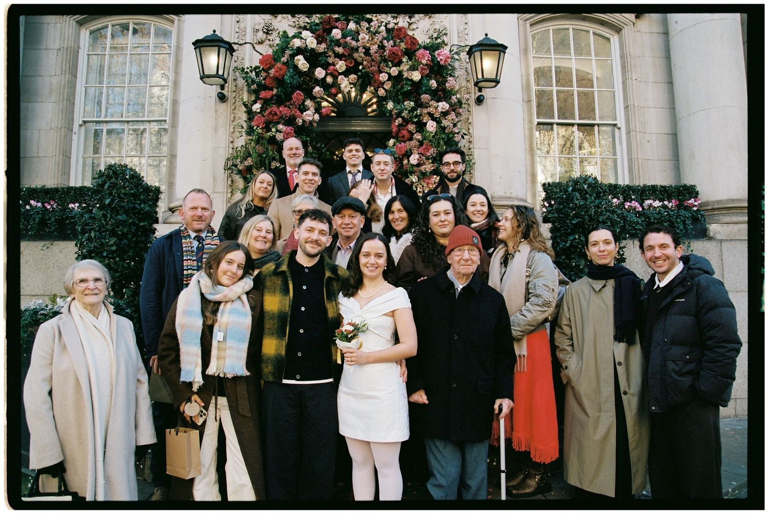 The wedding party & guests standing on the steps of Chelsea Old Town Hall