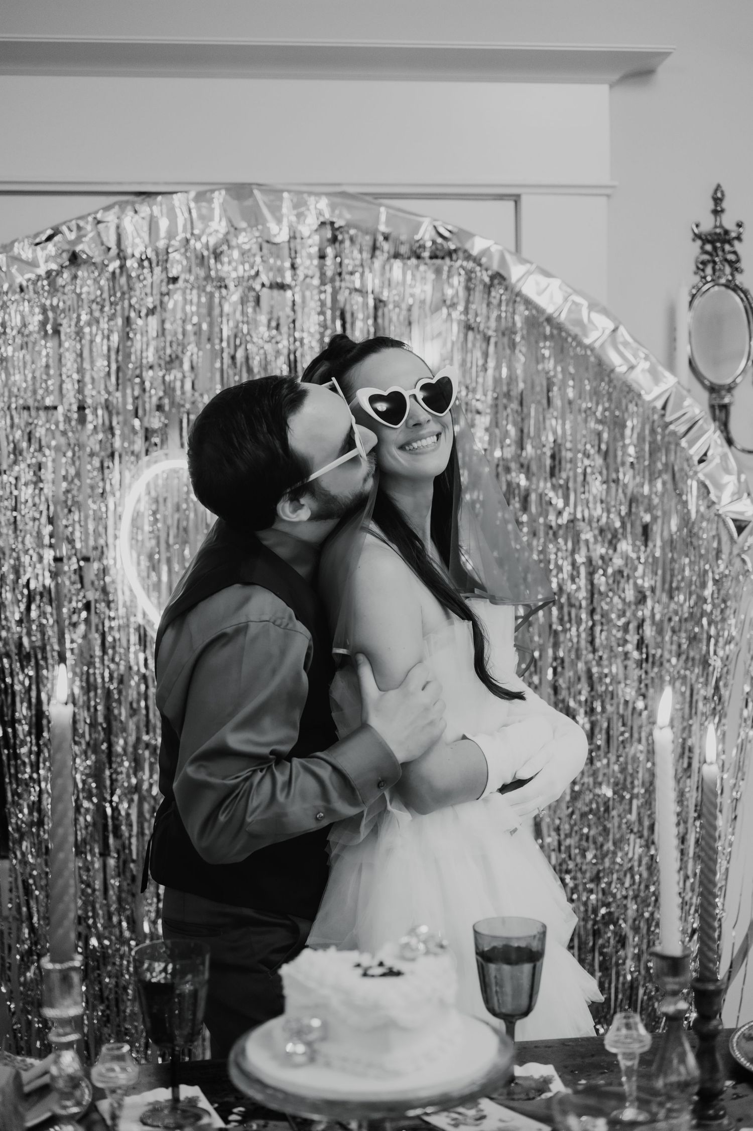 A celebratory moment in front of a silver tinsel backdrop with sunglasses and cake.