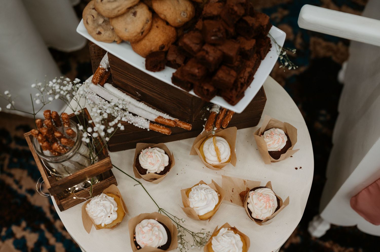 Rustic wedding dessert table with cupcakes, macarons and floral decorations.