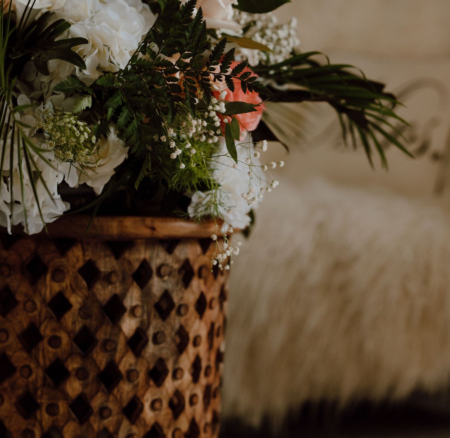 Textured copper vase filled with white and pink flowers against a soft blurred background.