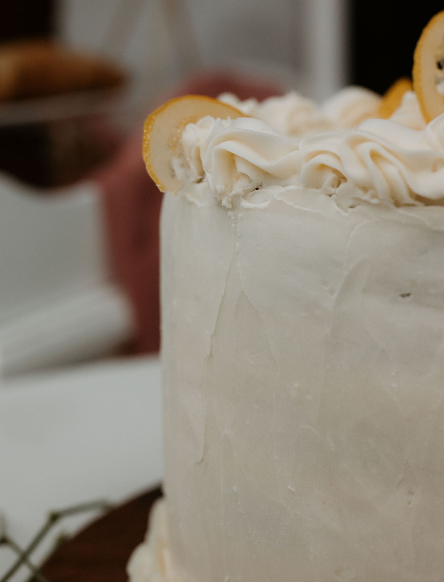 Close-up detail of a white wedding cake with smooth frosting and decorative piping.