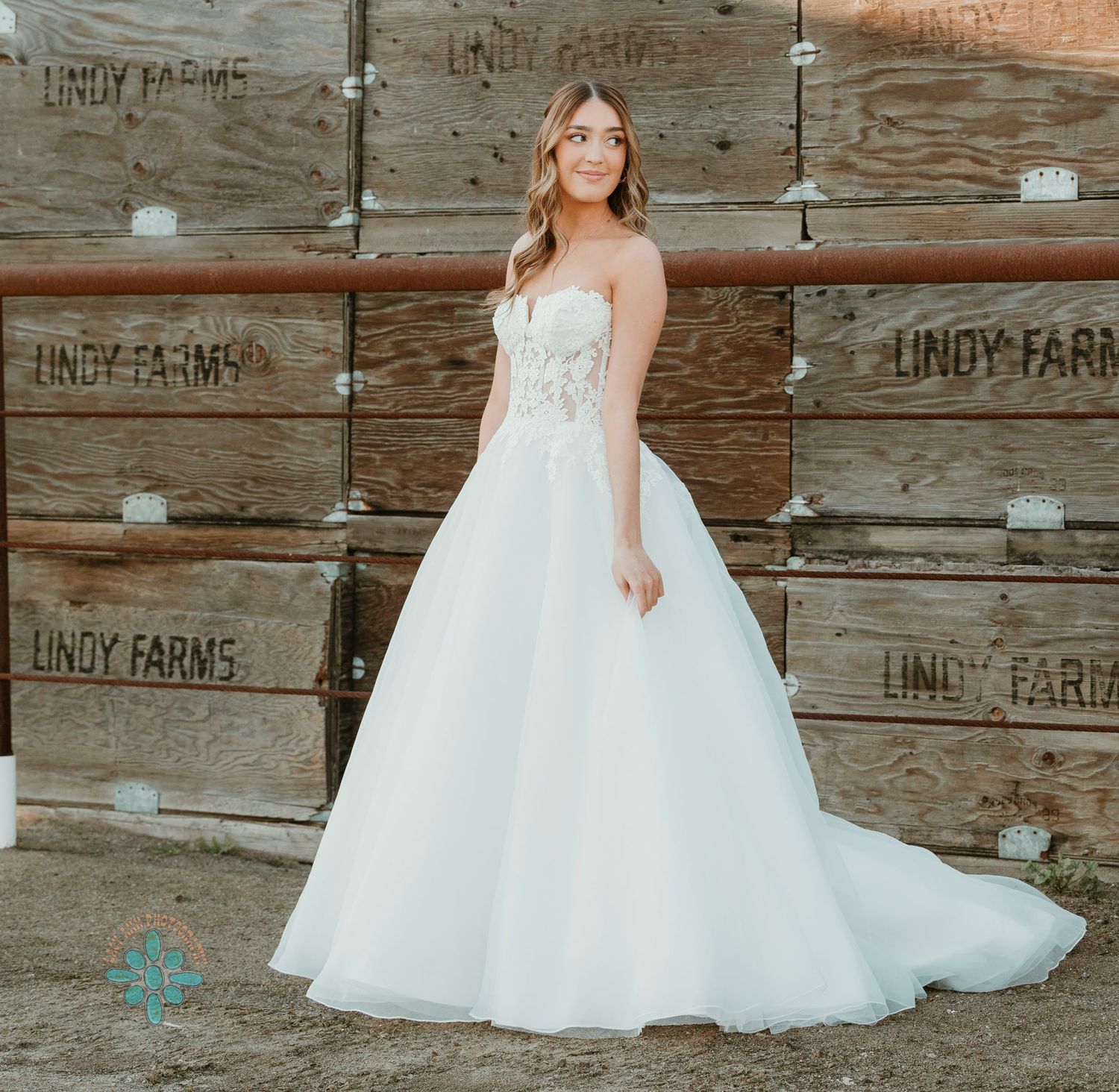 Elegant white ball gown wedding dress with lace details photographed against rustic wooden crates.