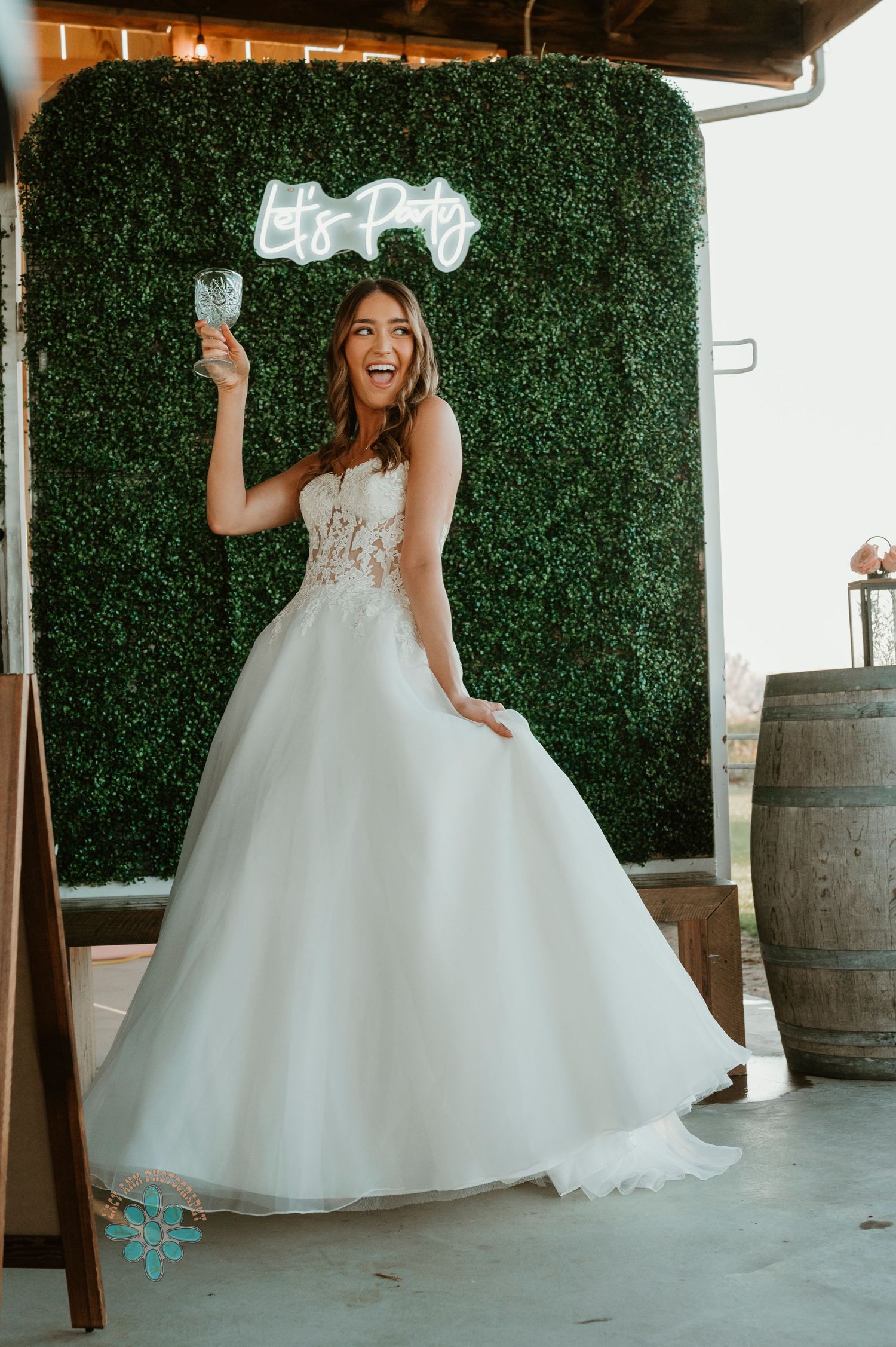 Wedding celebration scene with greenery wall backdrop and decorative wine barrel.