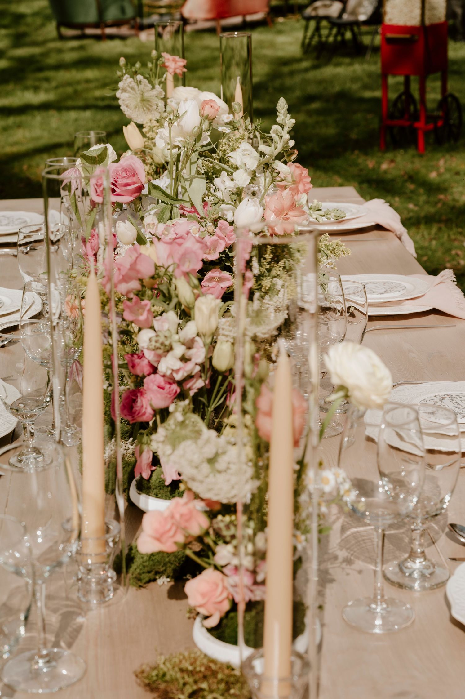 An elegant wedding table with pink and white floral arrangements and tall taper candles.