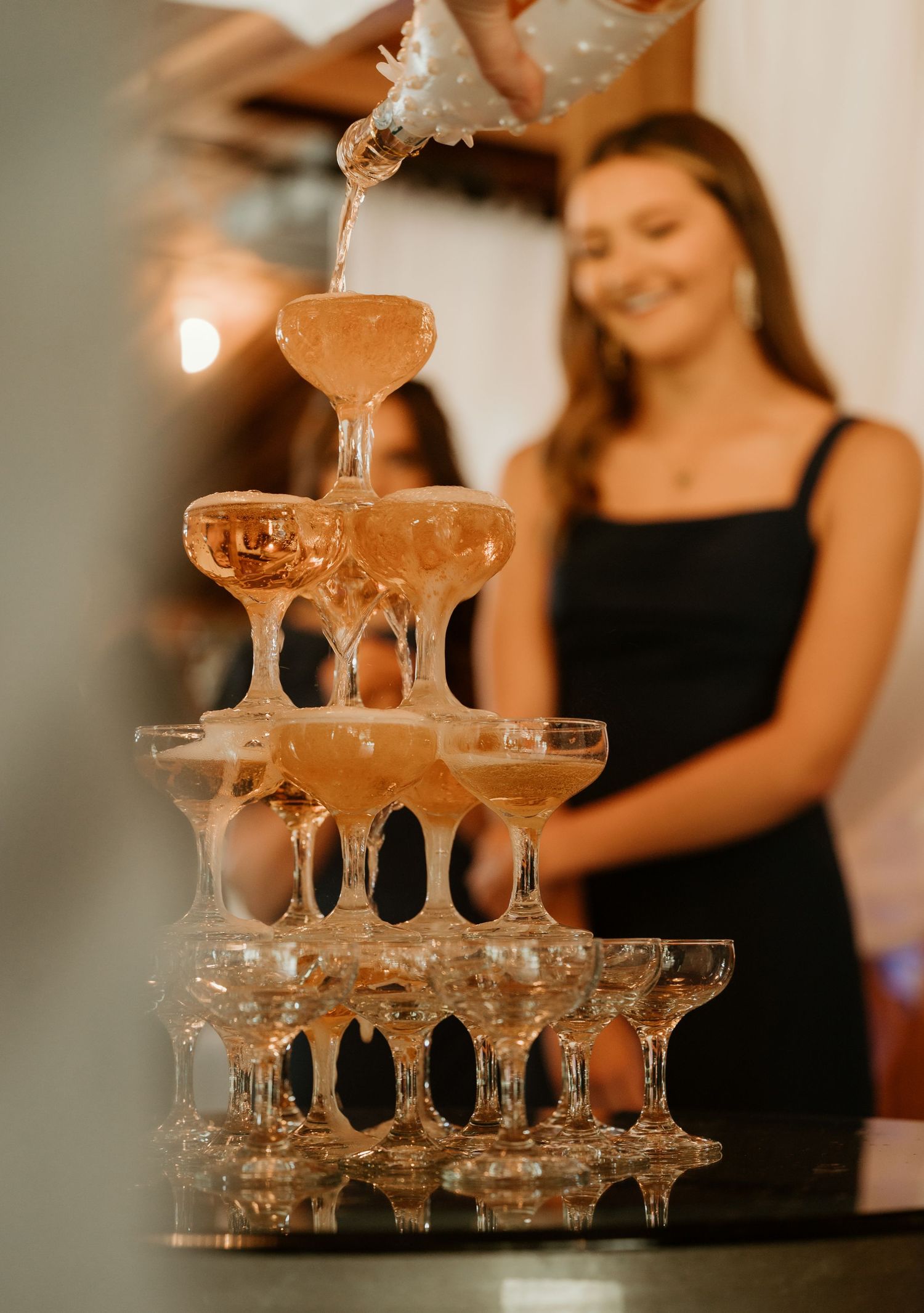Champagne being poured into a tower of coupe glasses creating an elegant cascade effect at an upscale event.