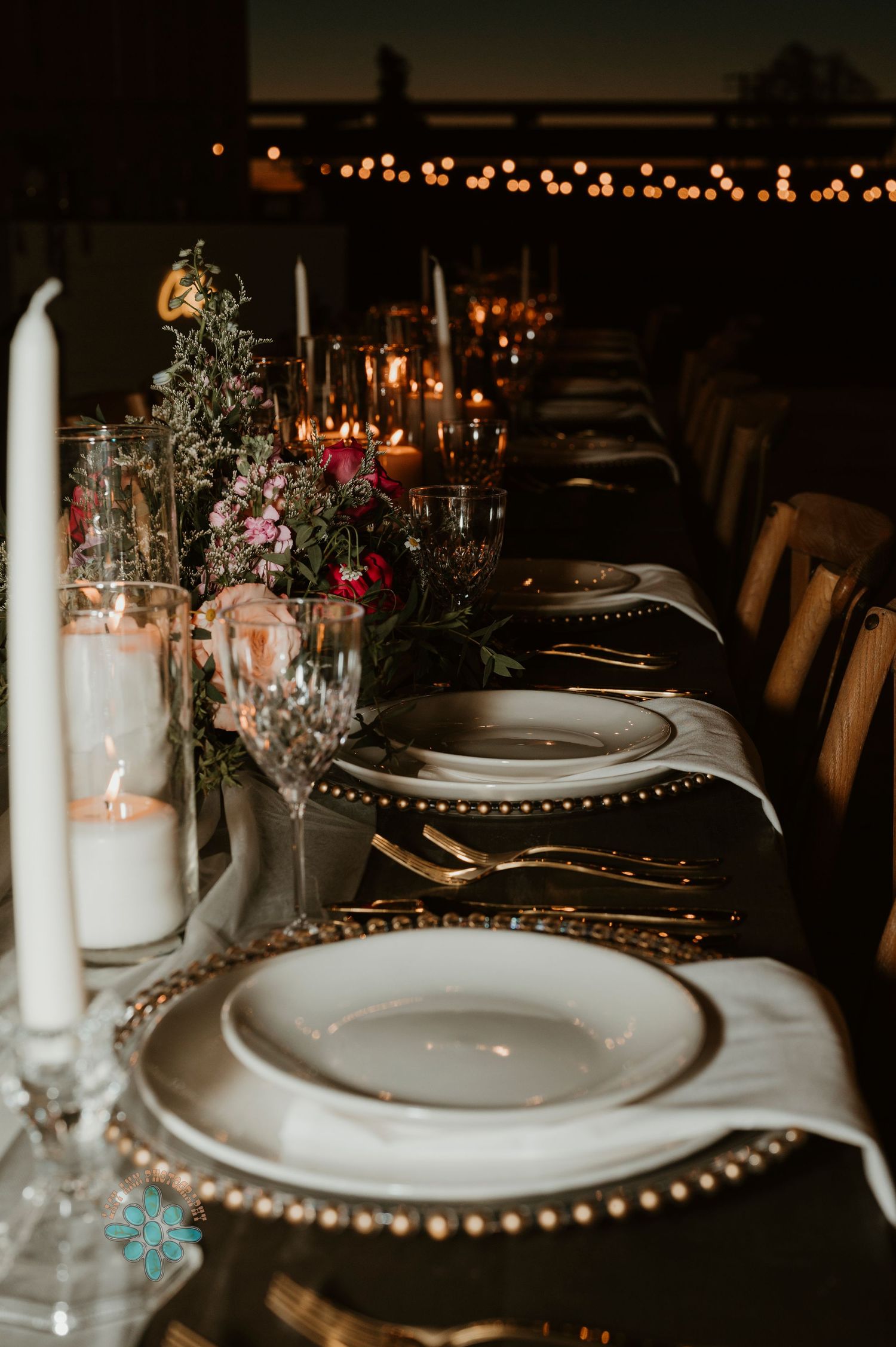 Elegant table setting with white plates, candles and floral centerpieces at a formal dinner.