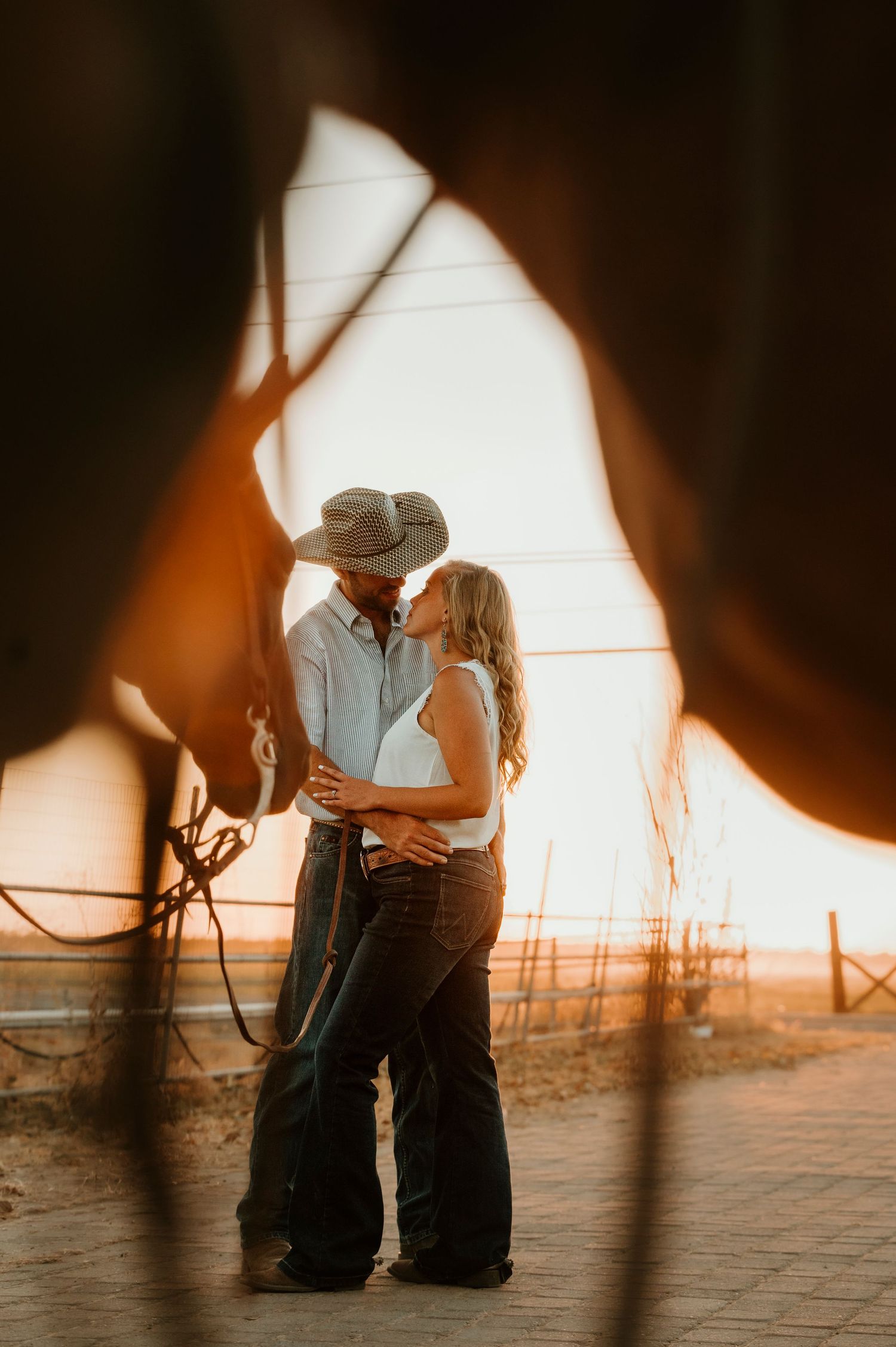 A romantic silhouette of a couple embracing in warm sunset light against a rustic backdrop.