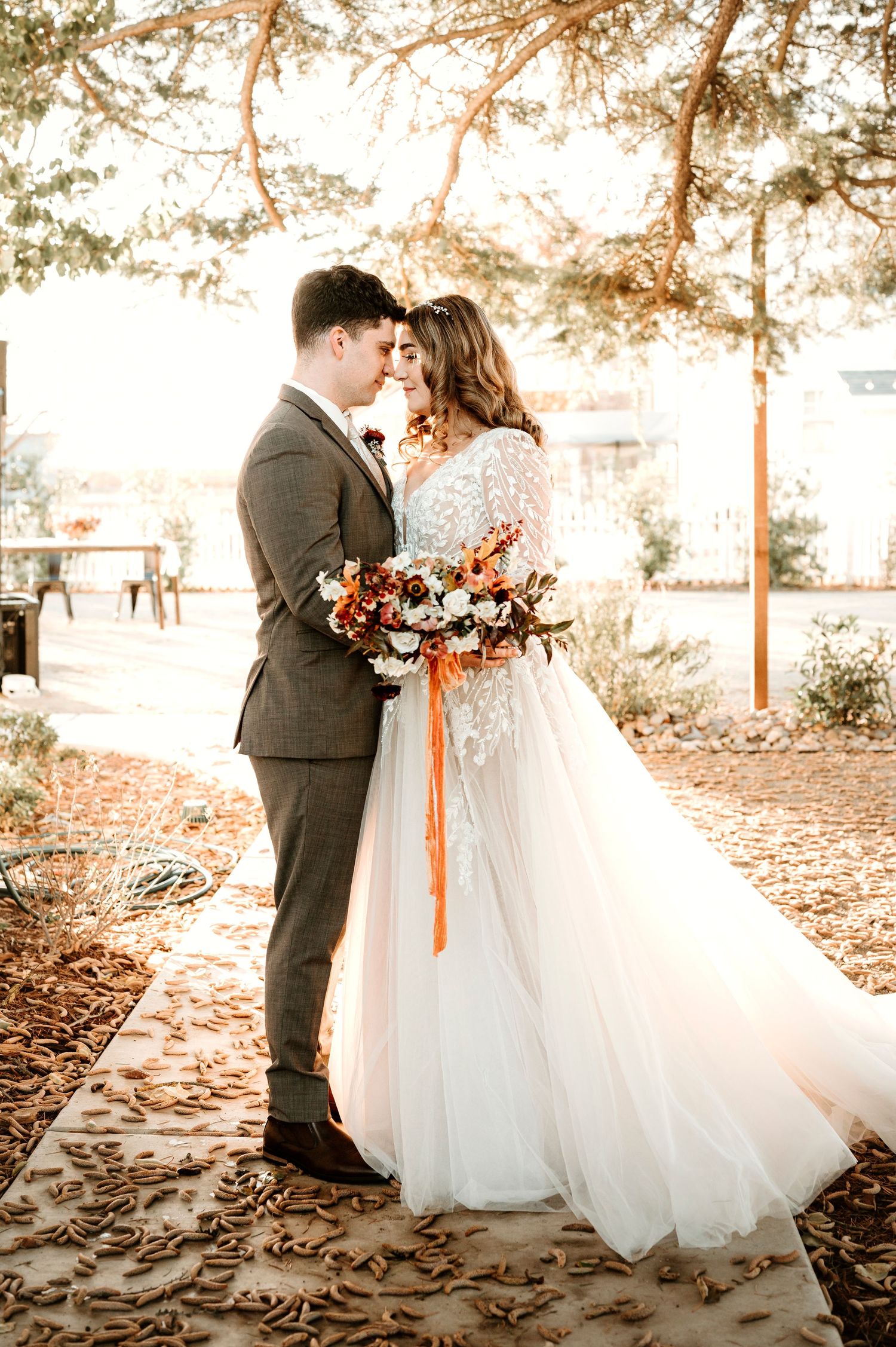 A romantic autumn wedding portrait with warm lighting and falling leaves.