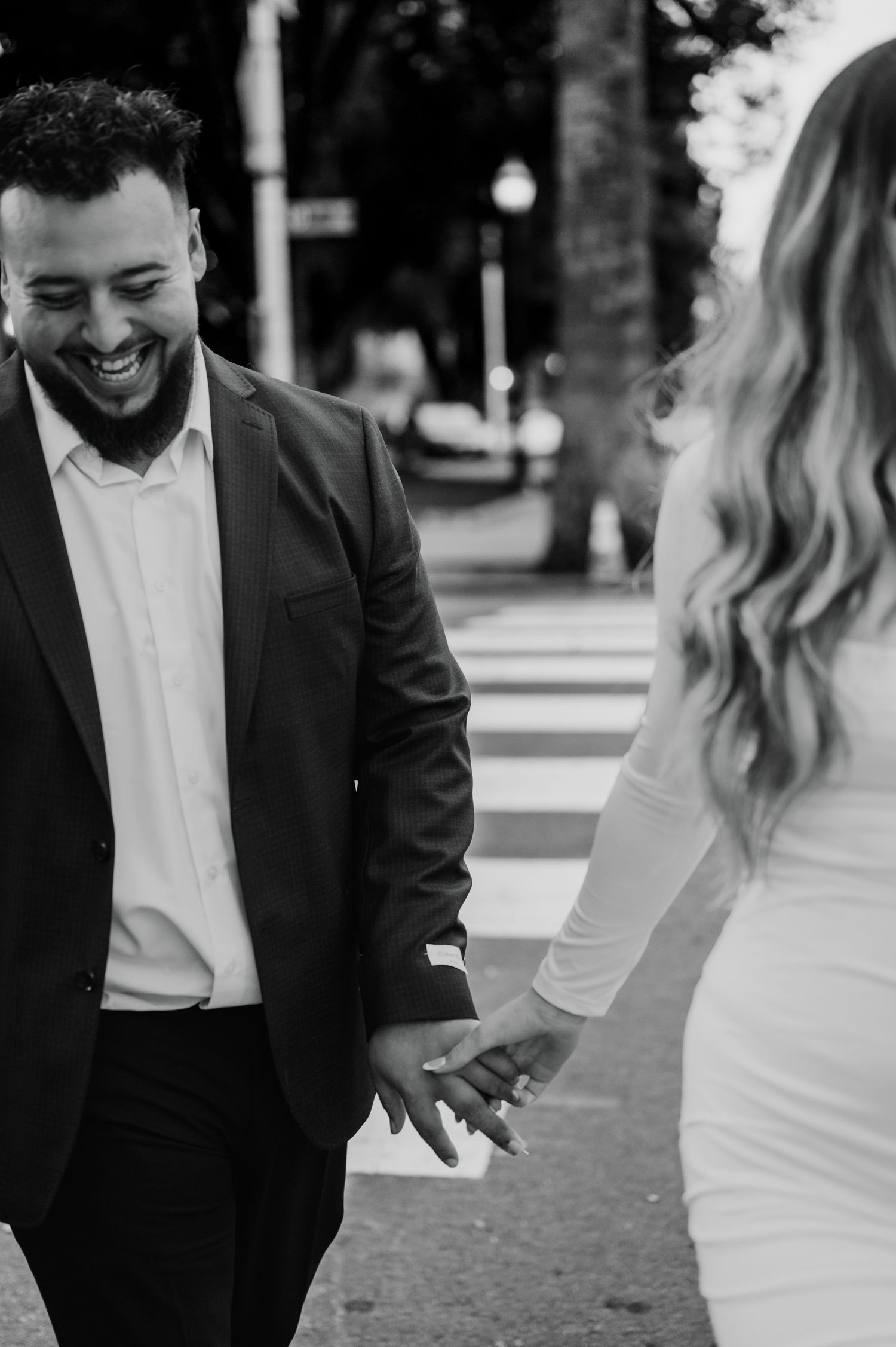 A candid black and white moment between a couple sharing laughter on a city street.