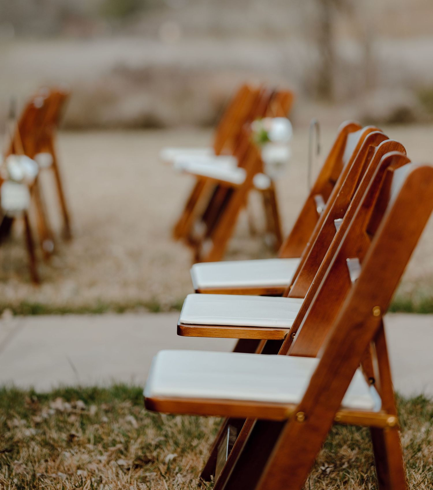 Row of wooden folding chairs set up for an outdoor ceremony.