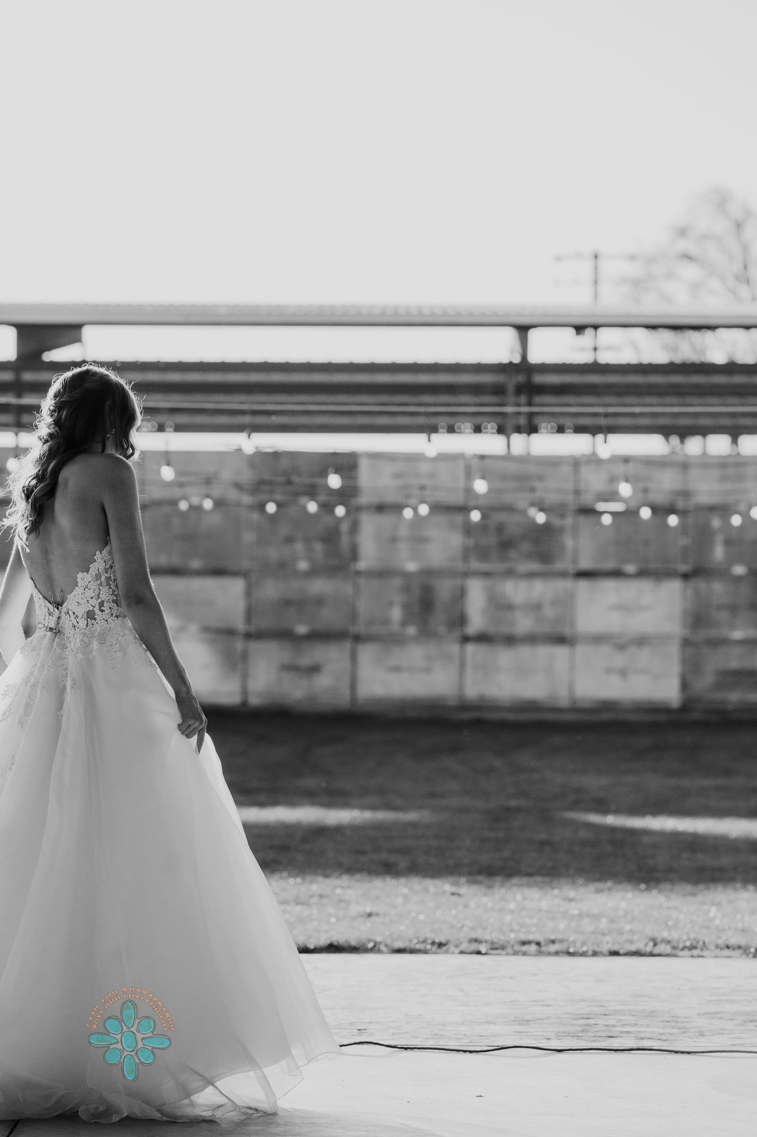 Elegant wedding dress silhouette against an industrial backdrop at sunset.