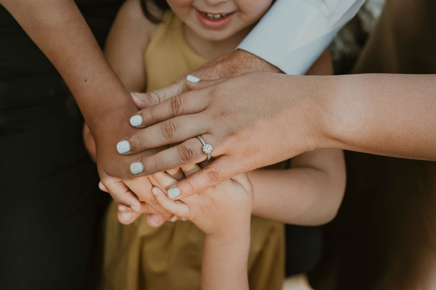 Multiple hands come together in unity showing teamwork and connection with light blue nail polish visible.
