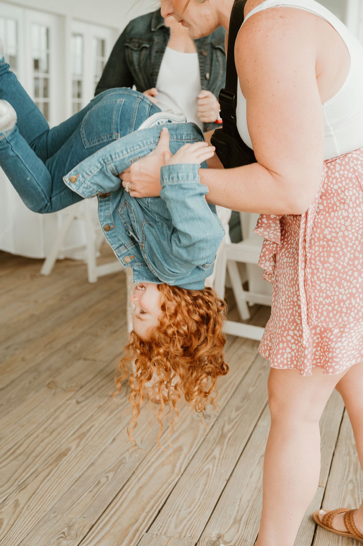 Playful moment with someone being held upside down, showing curly red hair.