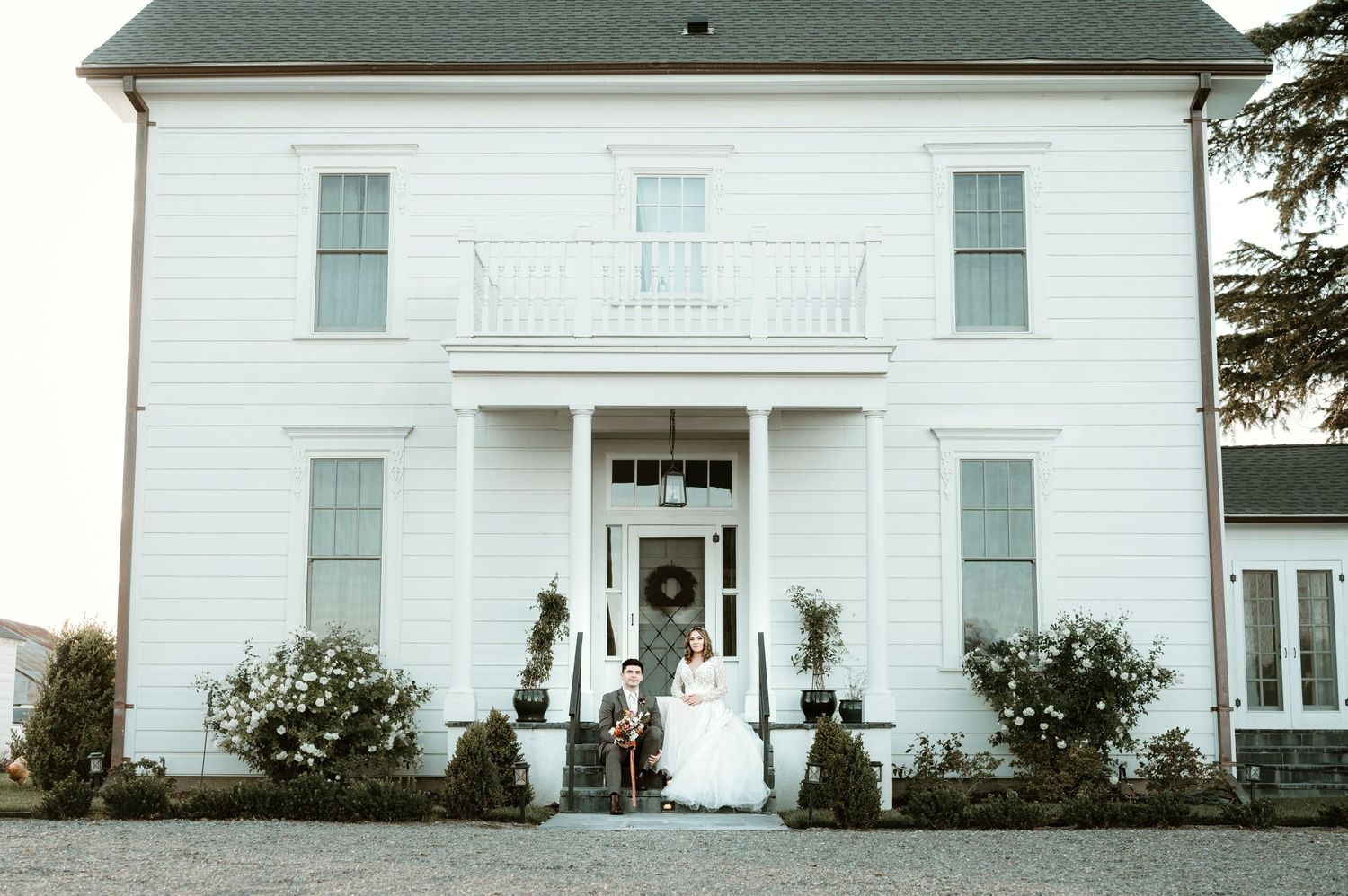A classic white two-story house with green shutters and a grand front porch entrance.