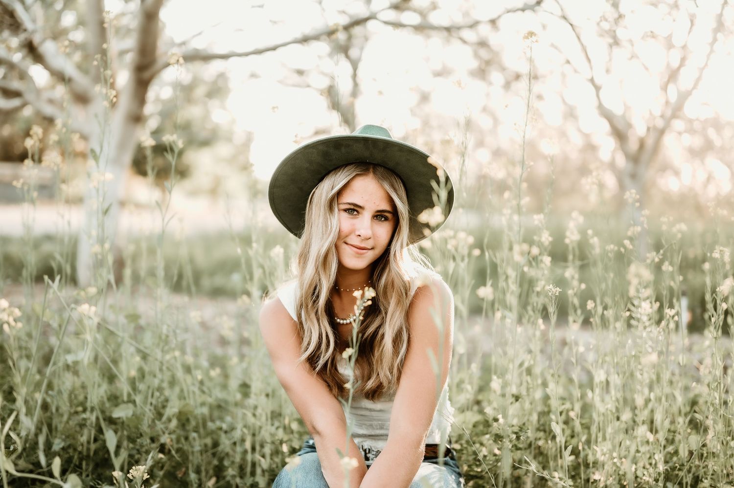 A collection of outdoor portrait photographs featuring someone sitting in a field during golden hour lighting.