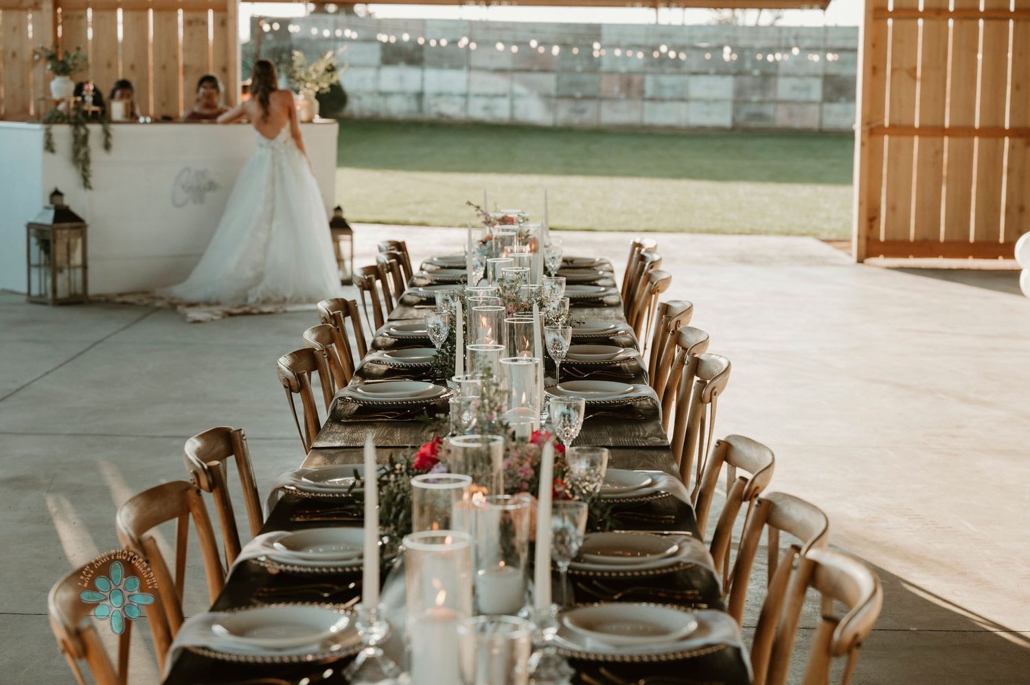 An elegant wedding reception table setup with wooden chairs and white linens.