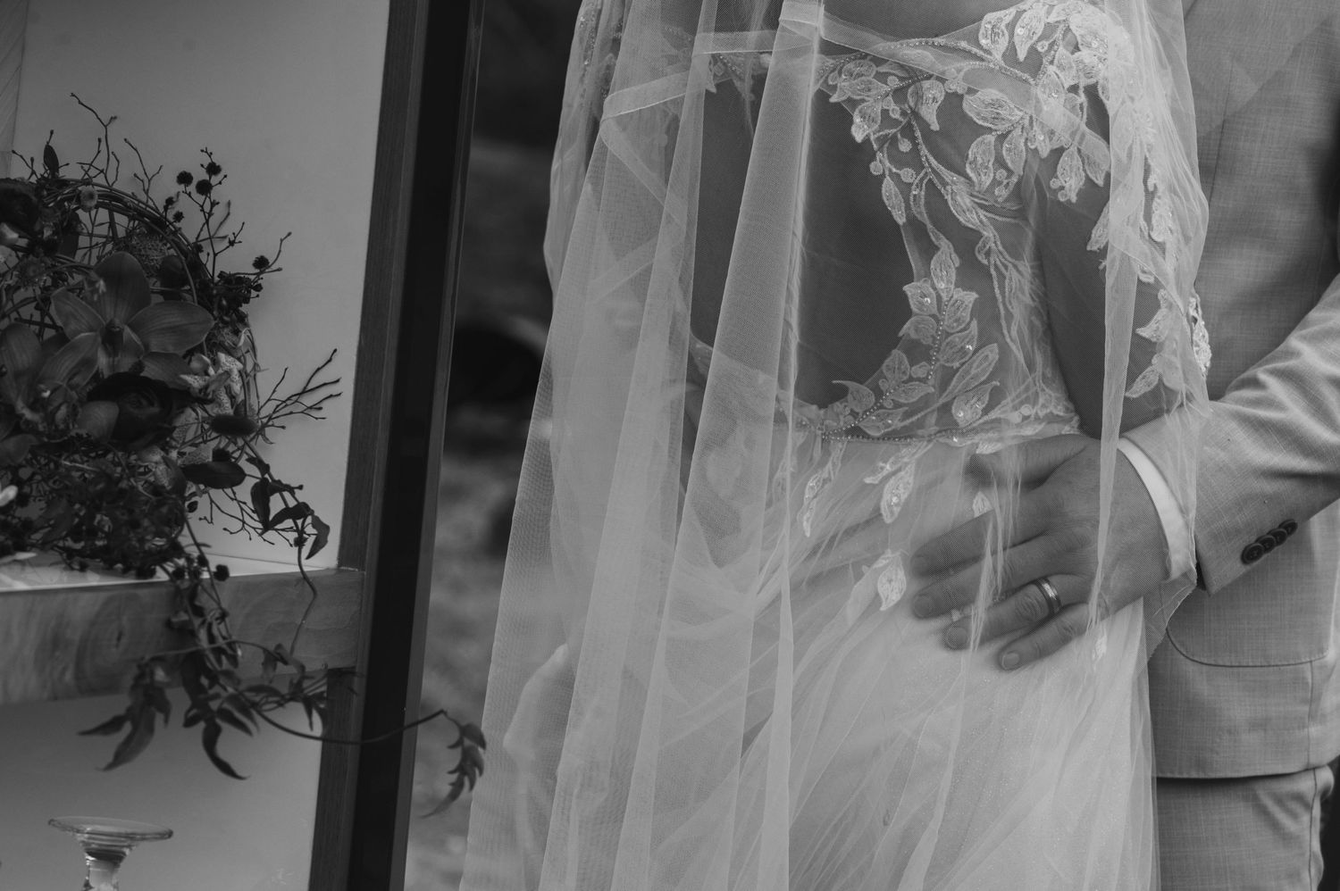 Black and white image of wedding bouquet and flowing veil details.