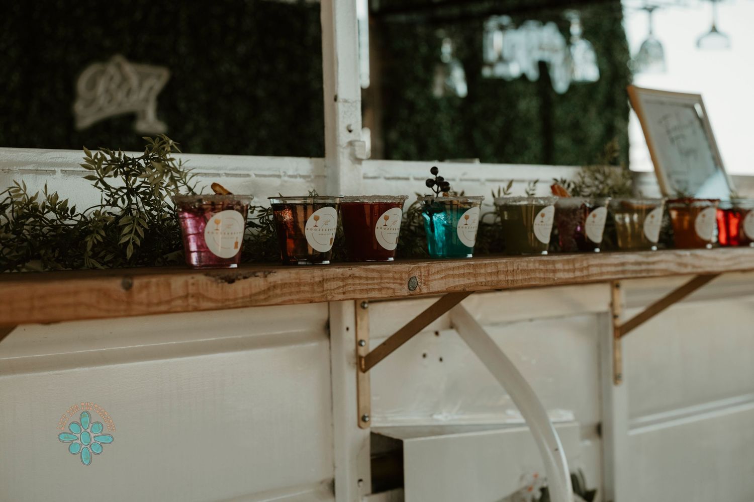 Colorful mason jar decorations lined up on a wooden shelf at a rustic wedding venue.