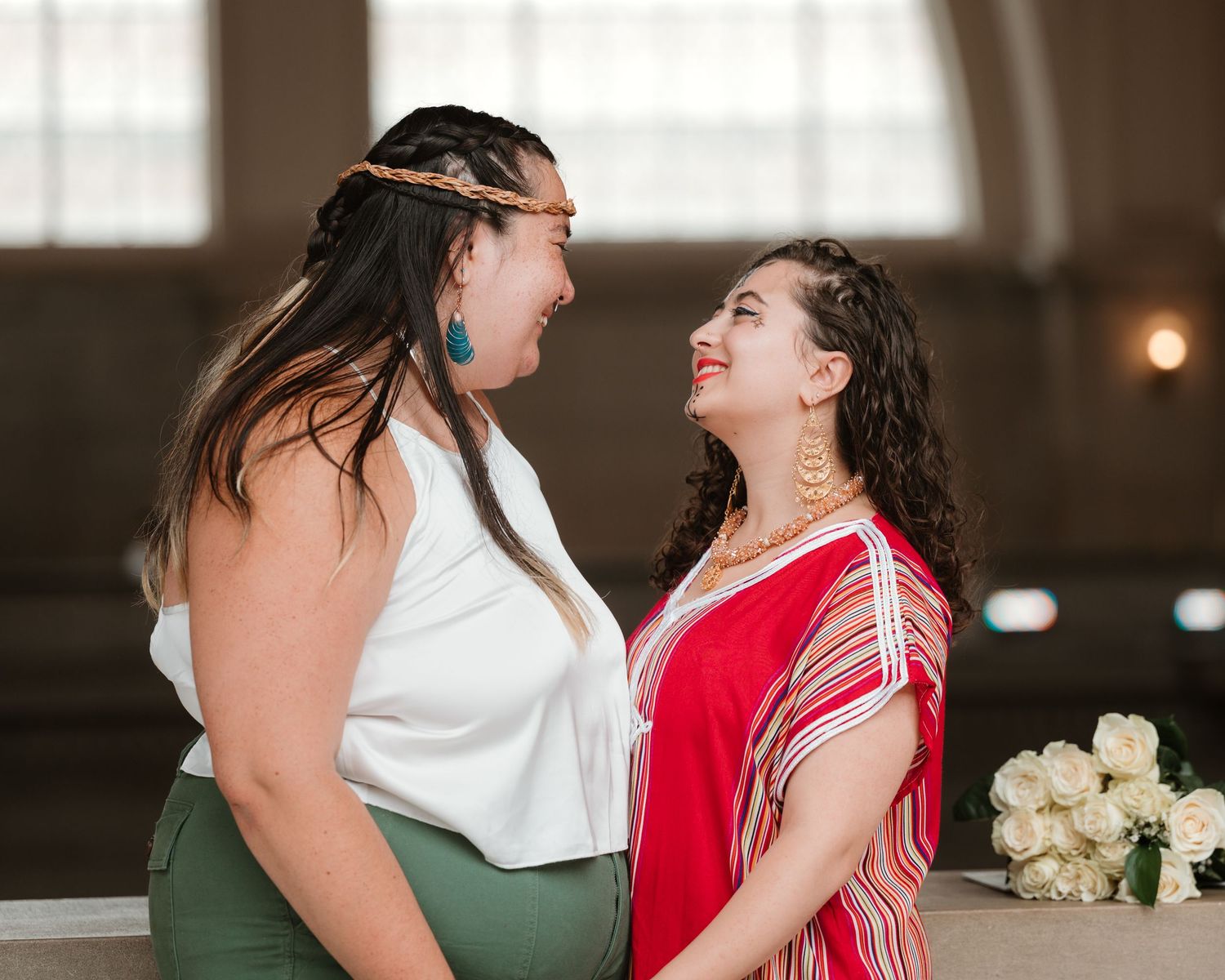 Two people share a joyful moment together while wearing contrasting white and red outfits at an indoor event.