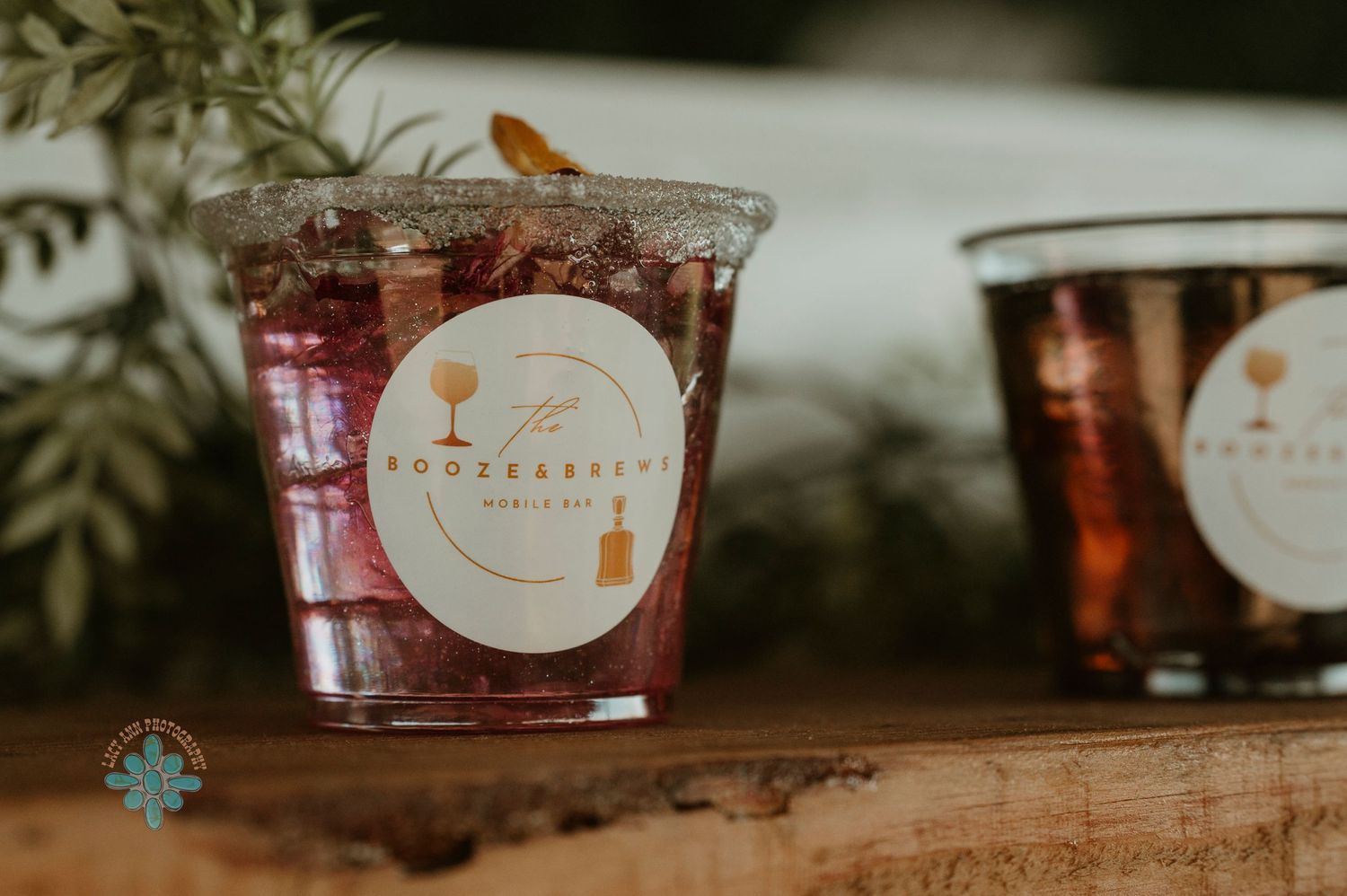 A glass of garnished cocktail with a branded sticker at a wedding bar.