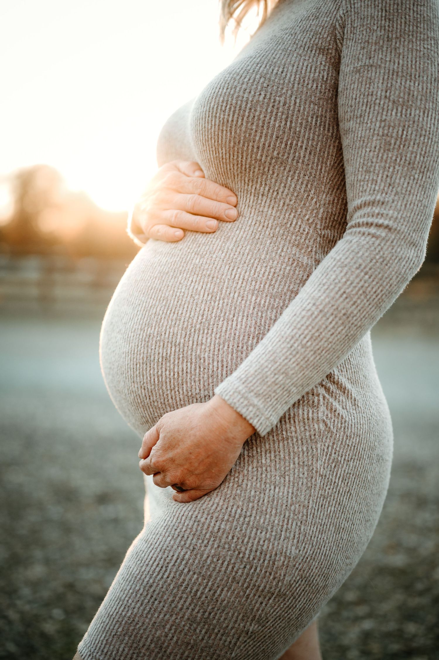 Close-up views of pregnant belly in grey sweater at sunset showing progression of pregnancy stages.
