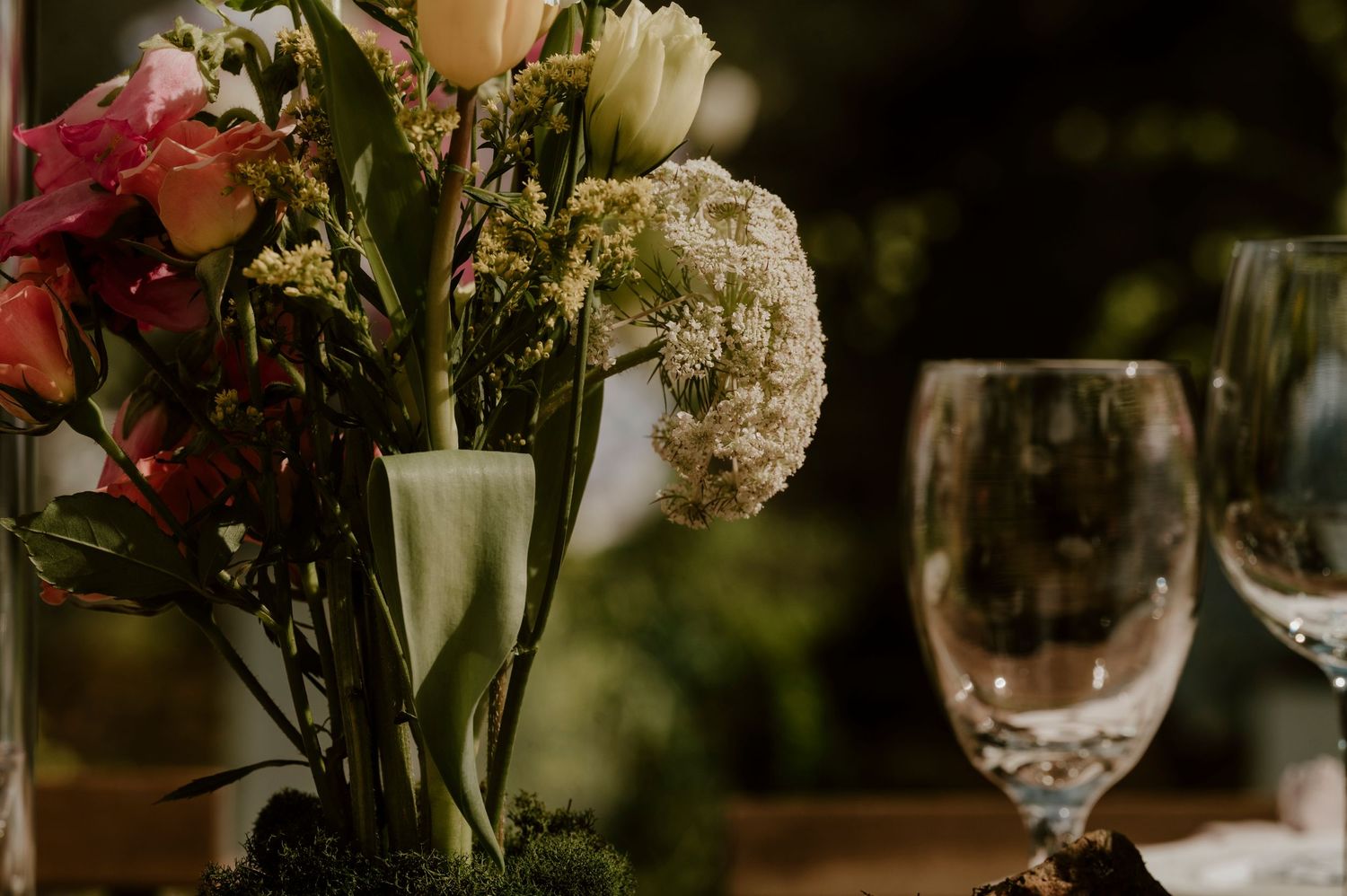 An elegant table setting with wine glasses and a floral centerpiece in soft focus.