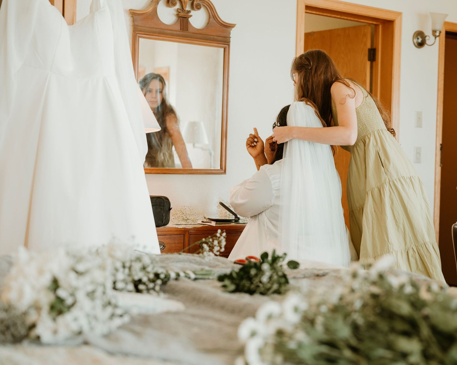 A wedding dress preparation scene with greenery decorations in a getting-ready room.