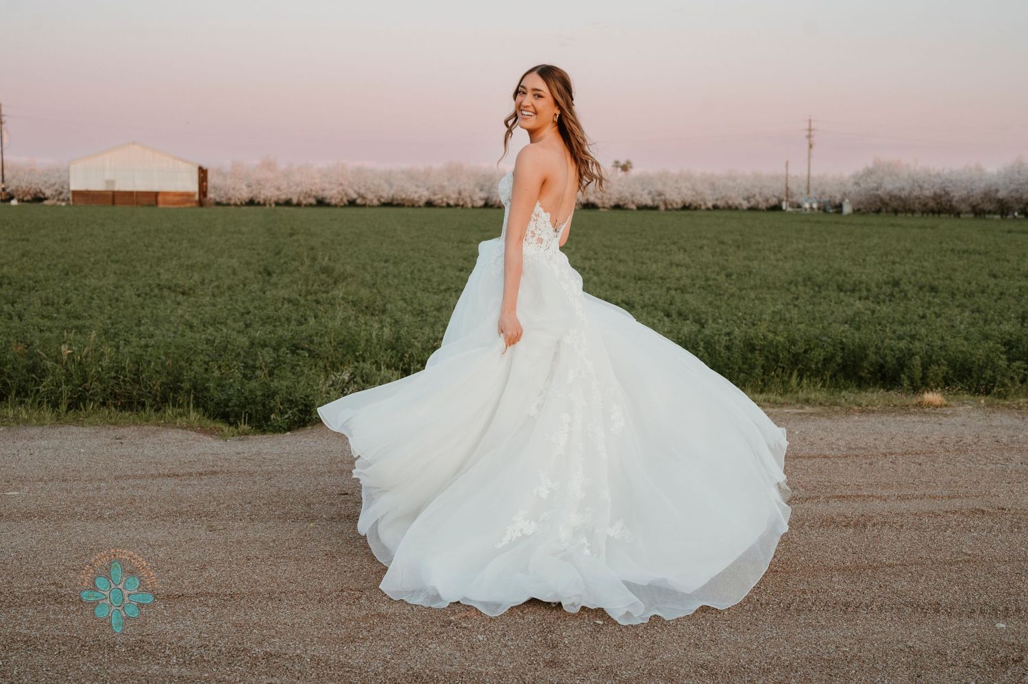 White wedding dress twirling dramatically in an outdoor field at sunset.