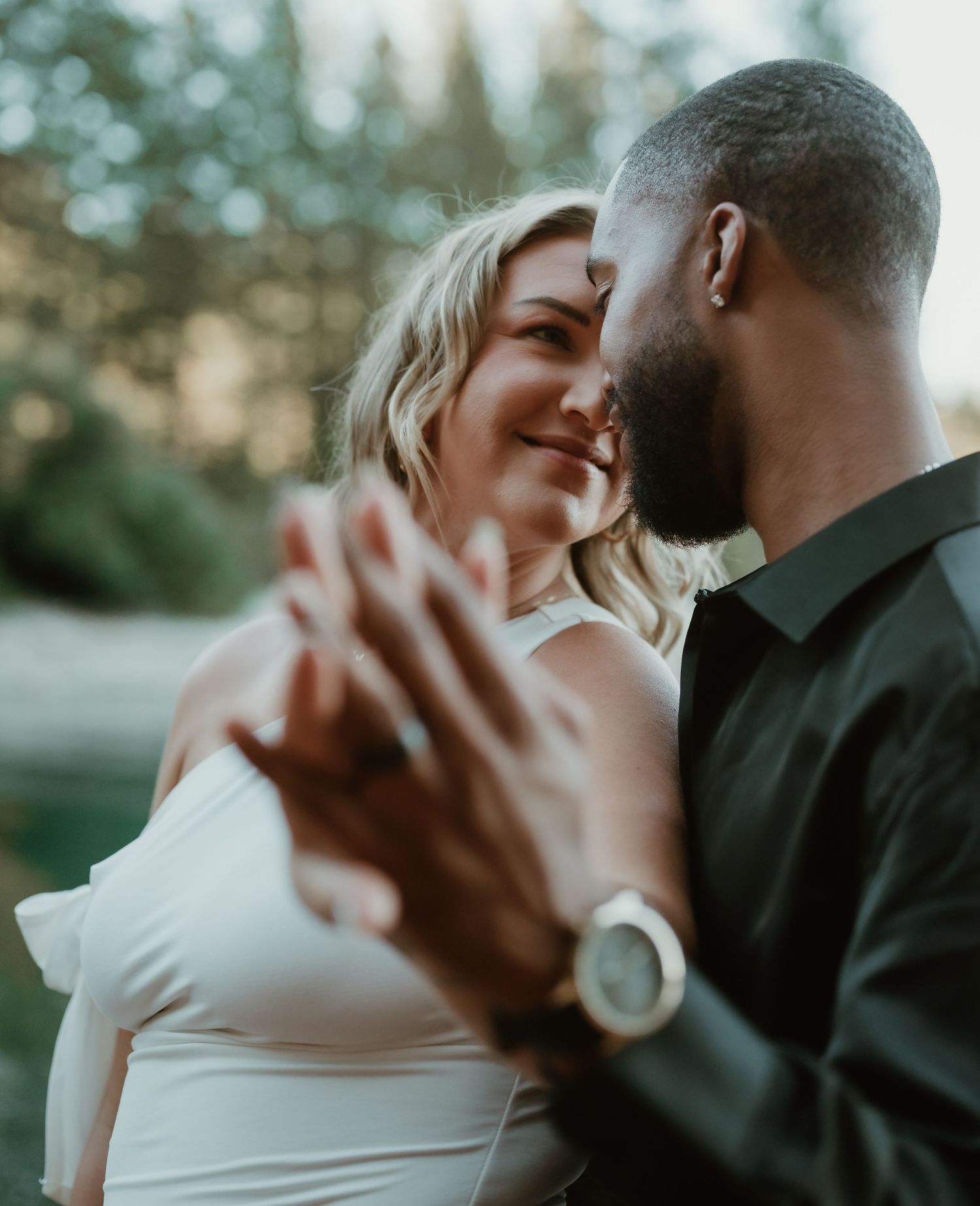 Romantic couple embraces and shares intimate moments in a soft outdoor setting during a wedding photo session.