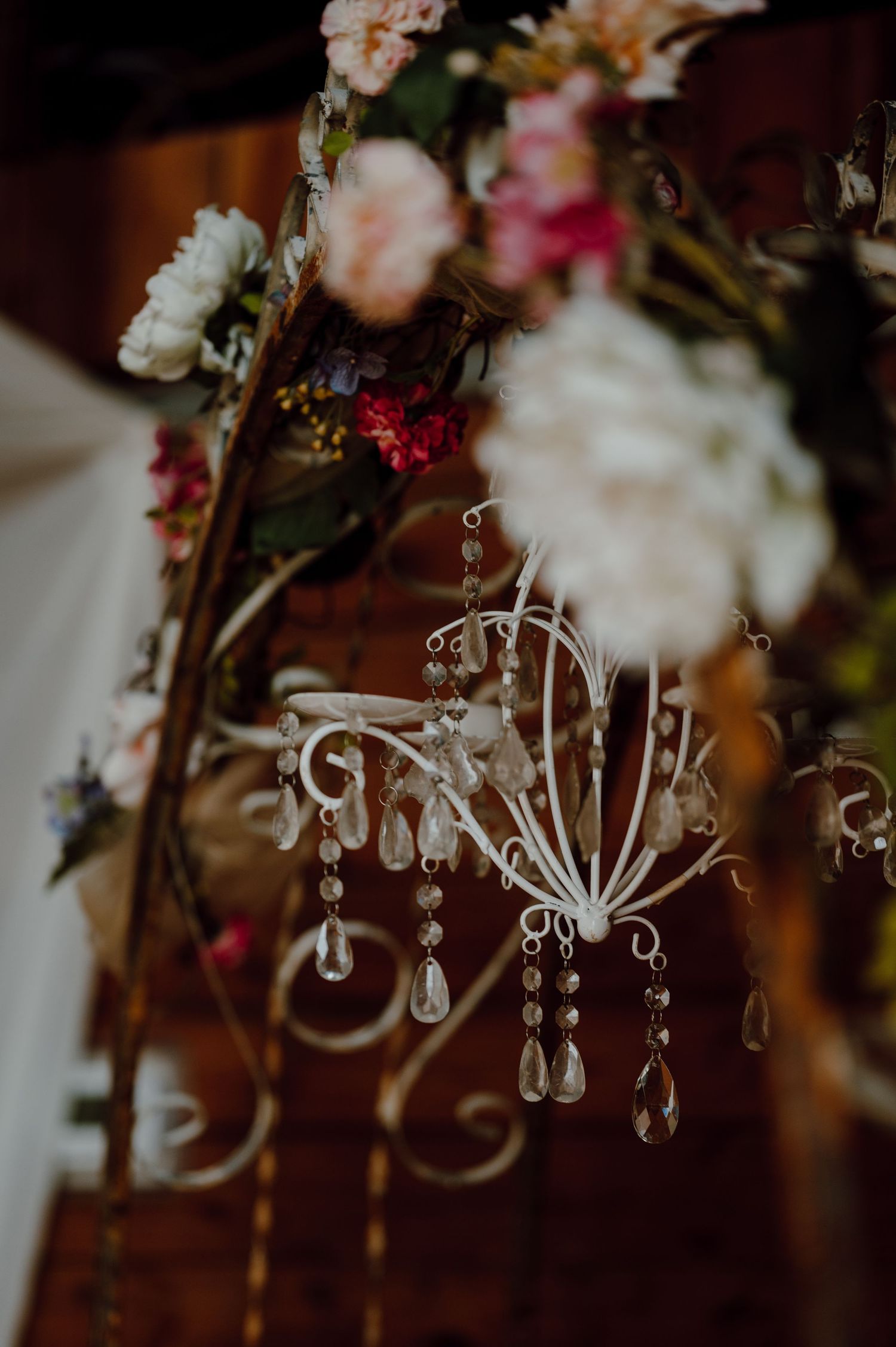 Crystal chandelier decoration with hanging crystals surrounded by romantic floral arrangements.