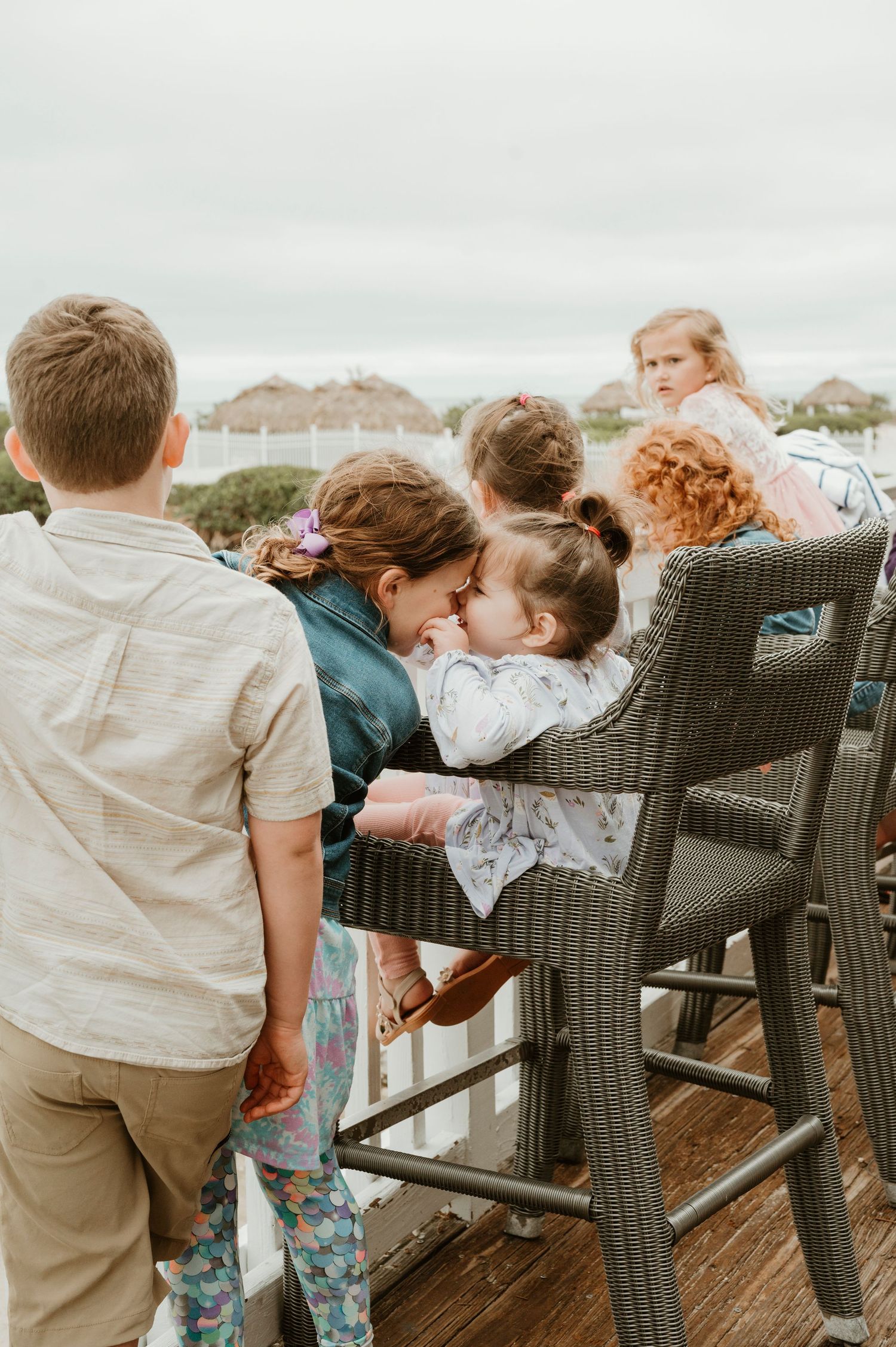 Group gathered around outdoor seating area with coastal view in background.