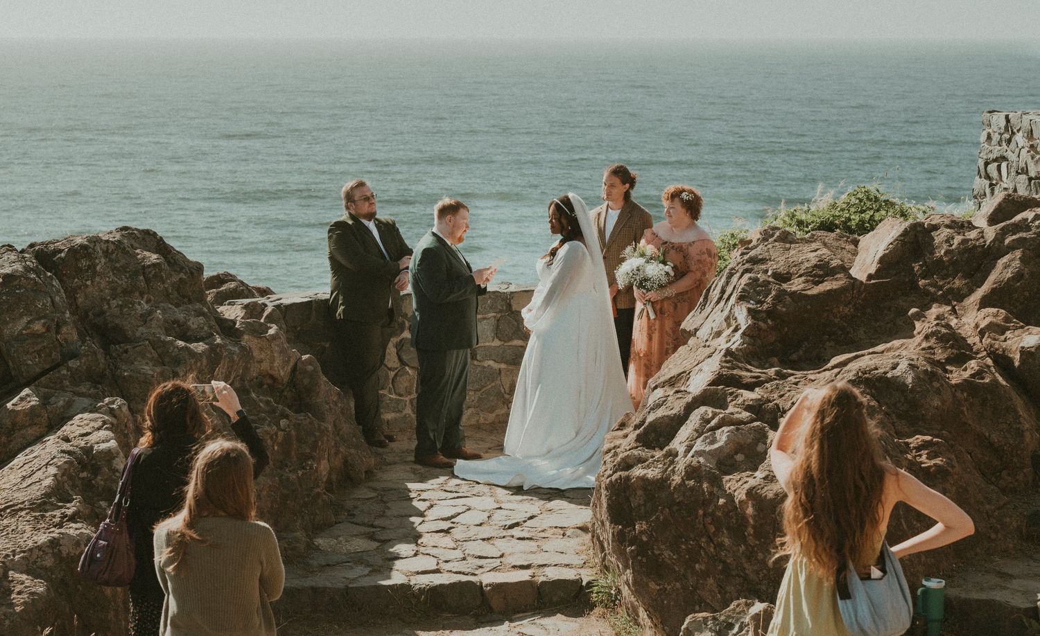 A seaside wedding ceremony taking place on dramatic rocky coastal cliffs.