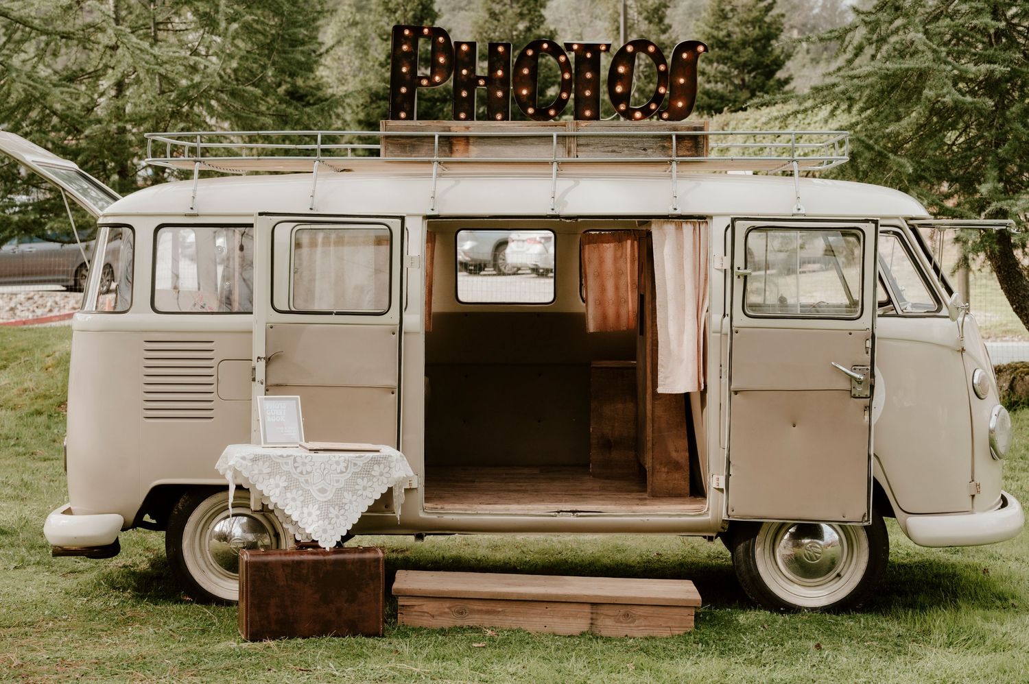 A vintage VW bus set up as a photo booth with fairy lights and rustic decorations.